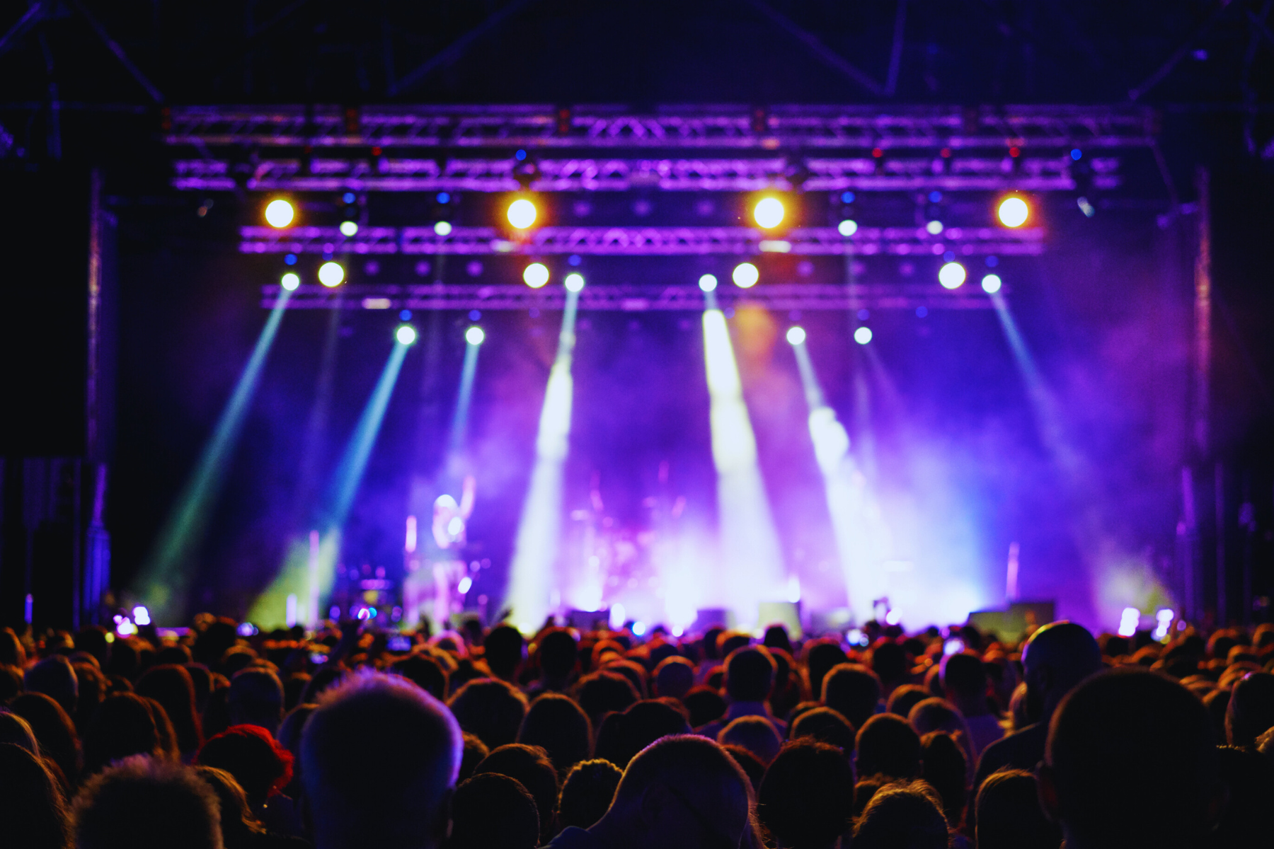 Crowd watching an outdoor concert with colorful stage lights at night