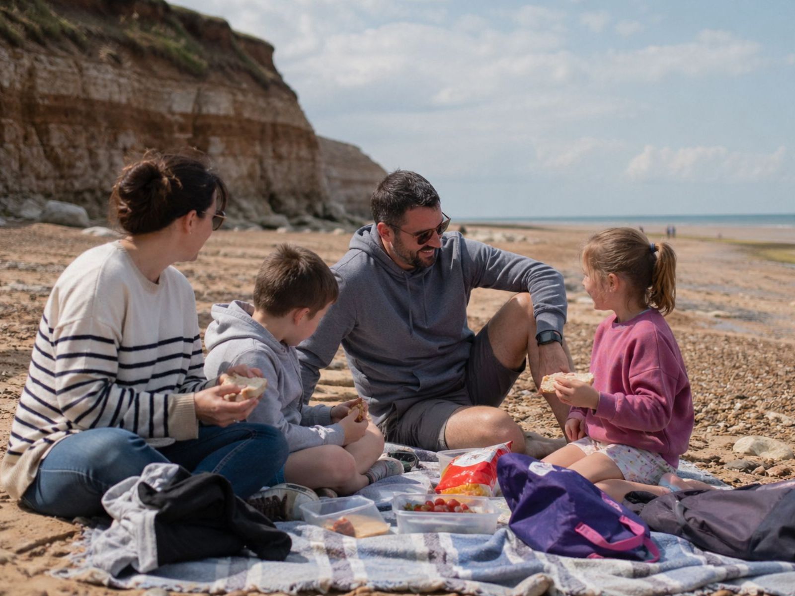 Family enjoying a picnic on a sandy beach beside the cliffs