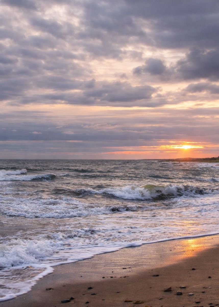Winter sunset over Hunstanton Beach with waves breaking on the shoreline beneath a cloudy sky