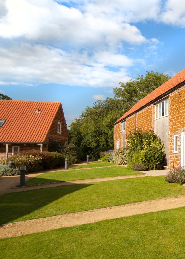 Brick cottage exterior with red tiled roof, timber cladding and landscaped garden under a blue sky