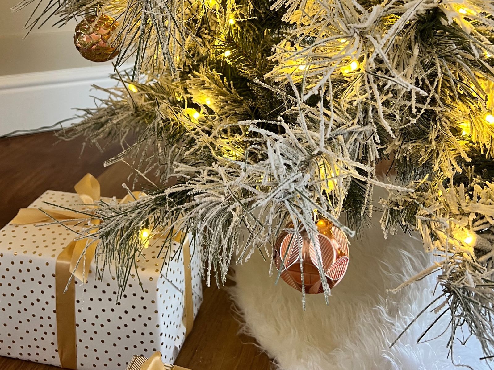 Close up of a snowy Christmas tree with bronze decorations and Christmas present