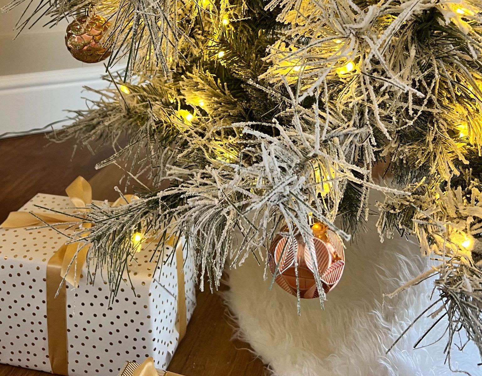 Close up of a snowy Christmas tree with bronze decorations and Christmas present