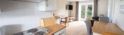 Open plan kitchenette and living area decorated in neutral tones, with french doors facing a duck pond