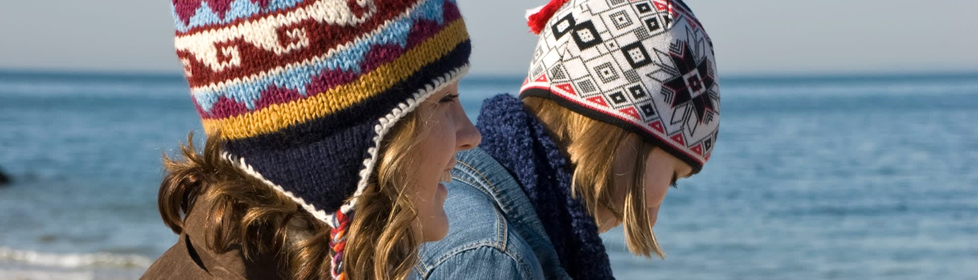 Female couple dressed in winter clothing walking on a pebble beach