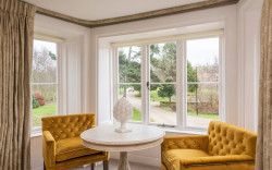 Luxury hotel room seating in front of a bay window with views of winding drive and gardens