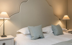 Luxury hotel room bed with bespoke blue headboard and matching accent pillows