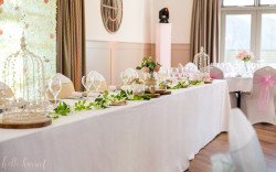 Bright and airy function space set up for a wedding showing head table decorated in foliage