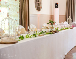 Bright and airy function space set up for a wedding showing head table decorated in foliage