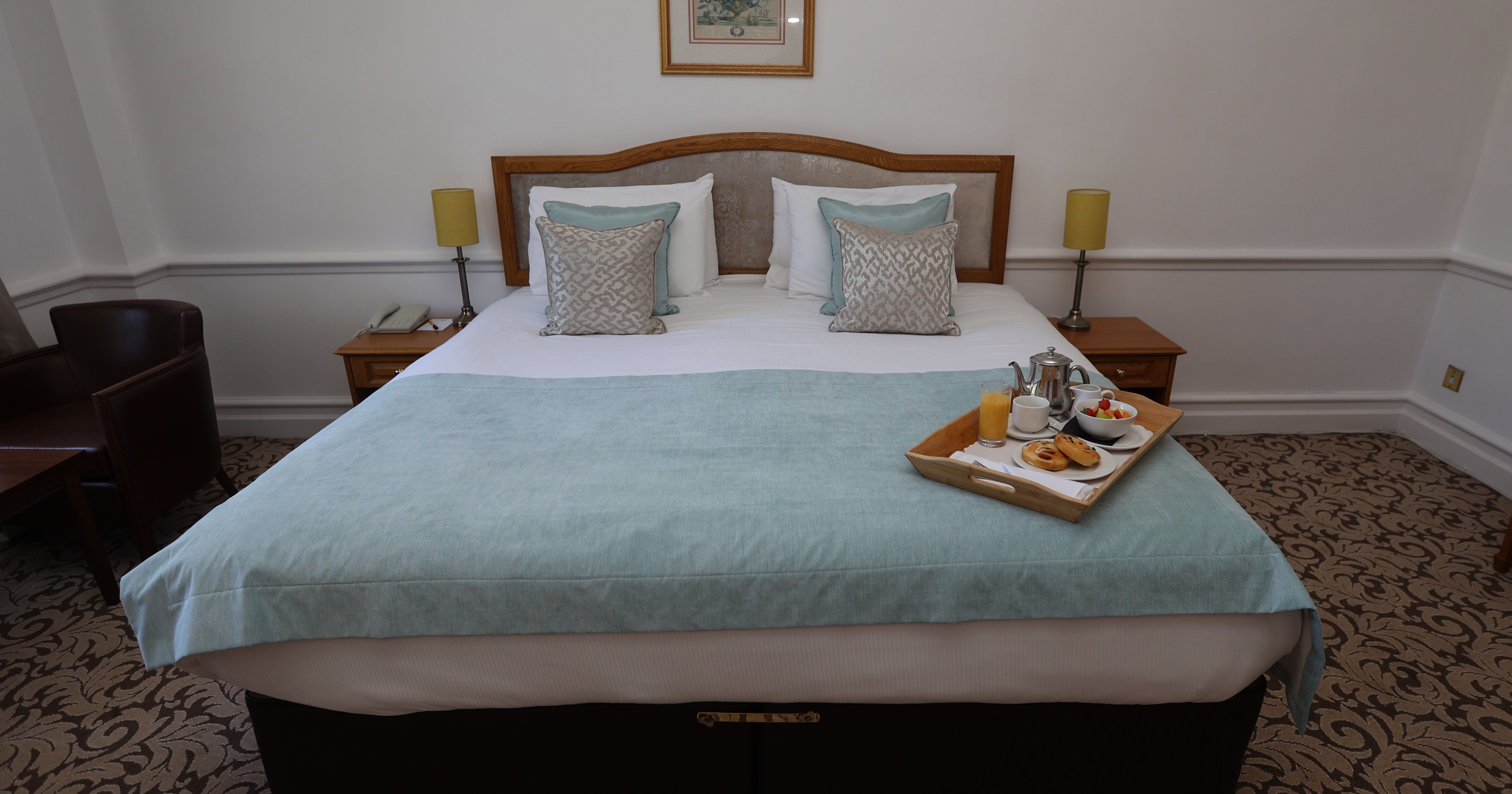 A neatly made hotel bed with a breakfast tray on top.
