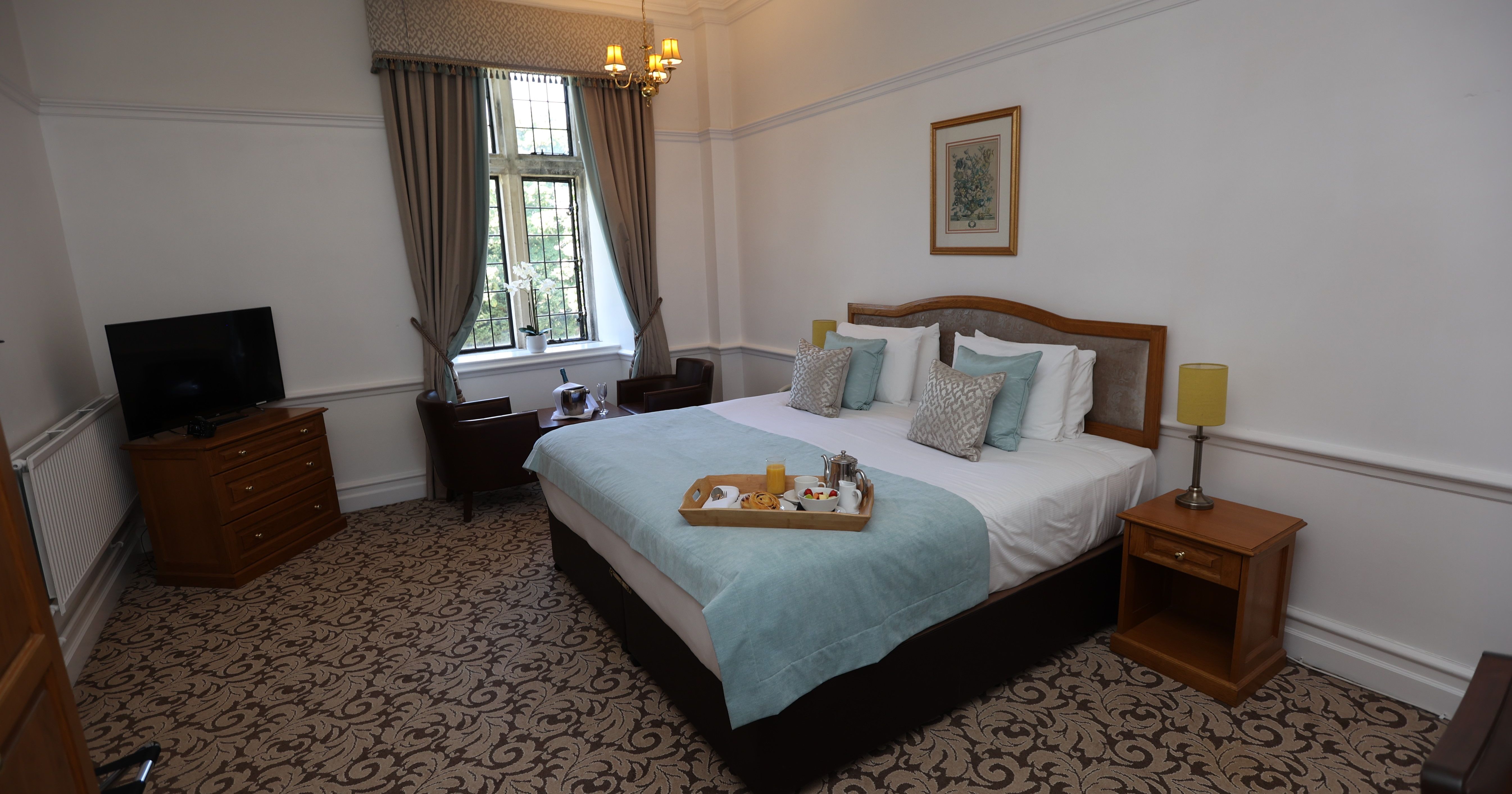 A cozy hotel room with a large bed, elegant decor, and a breakfast tray