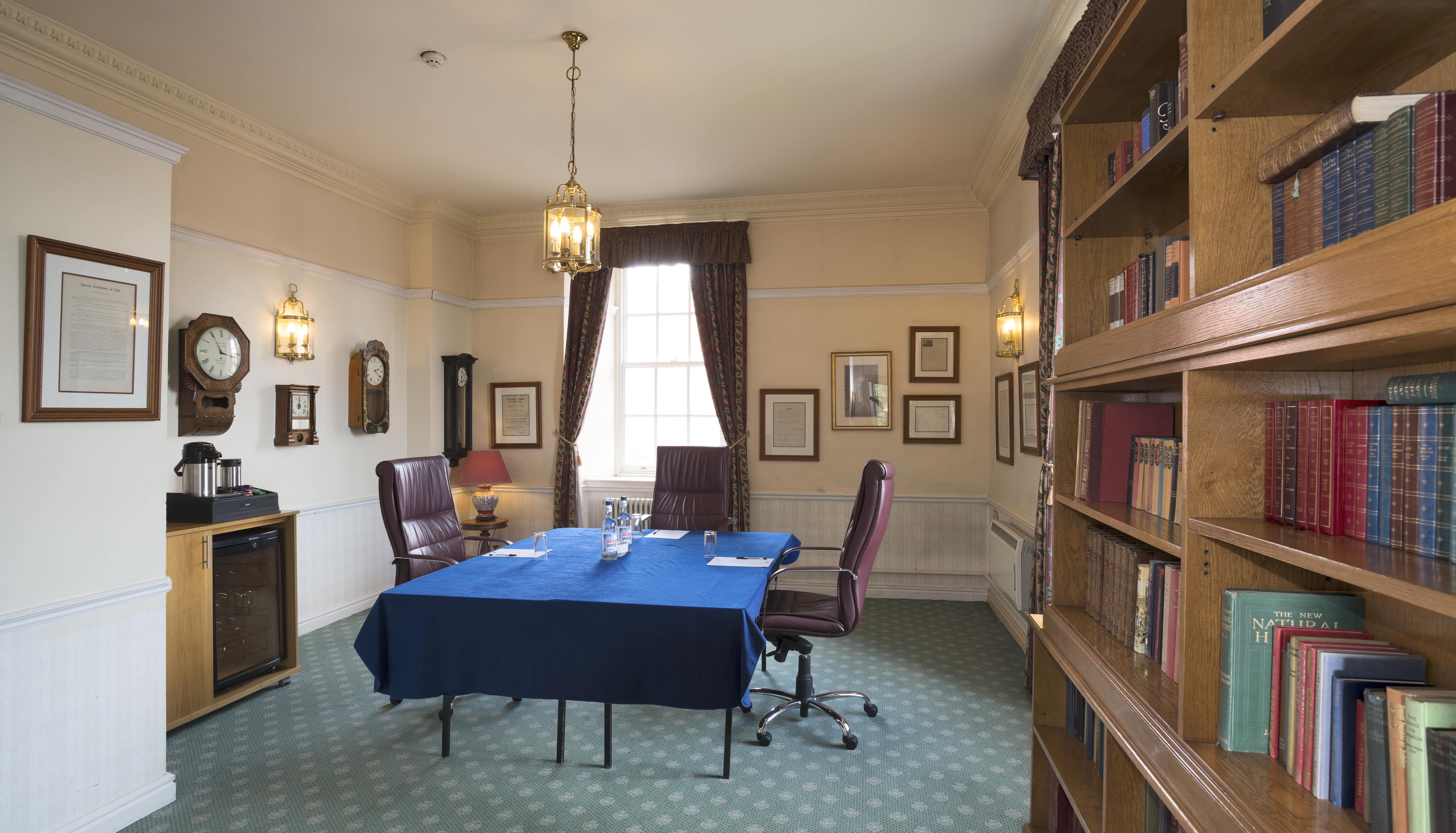 Traditional meeting room with bookshelf, table, and leather chairs