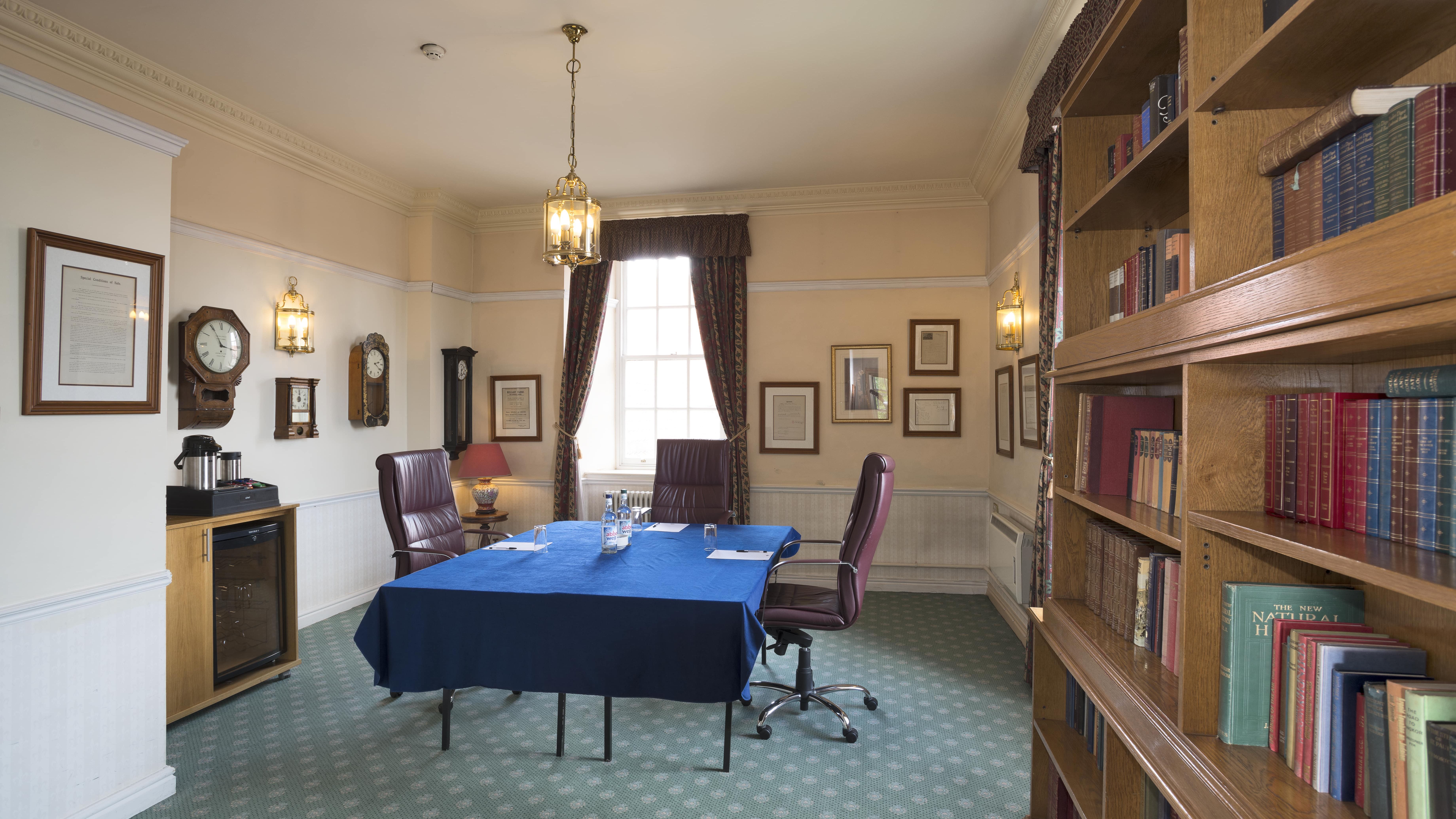 Traditional meeting room with bookshelf, table, and leather chairs