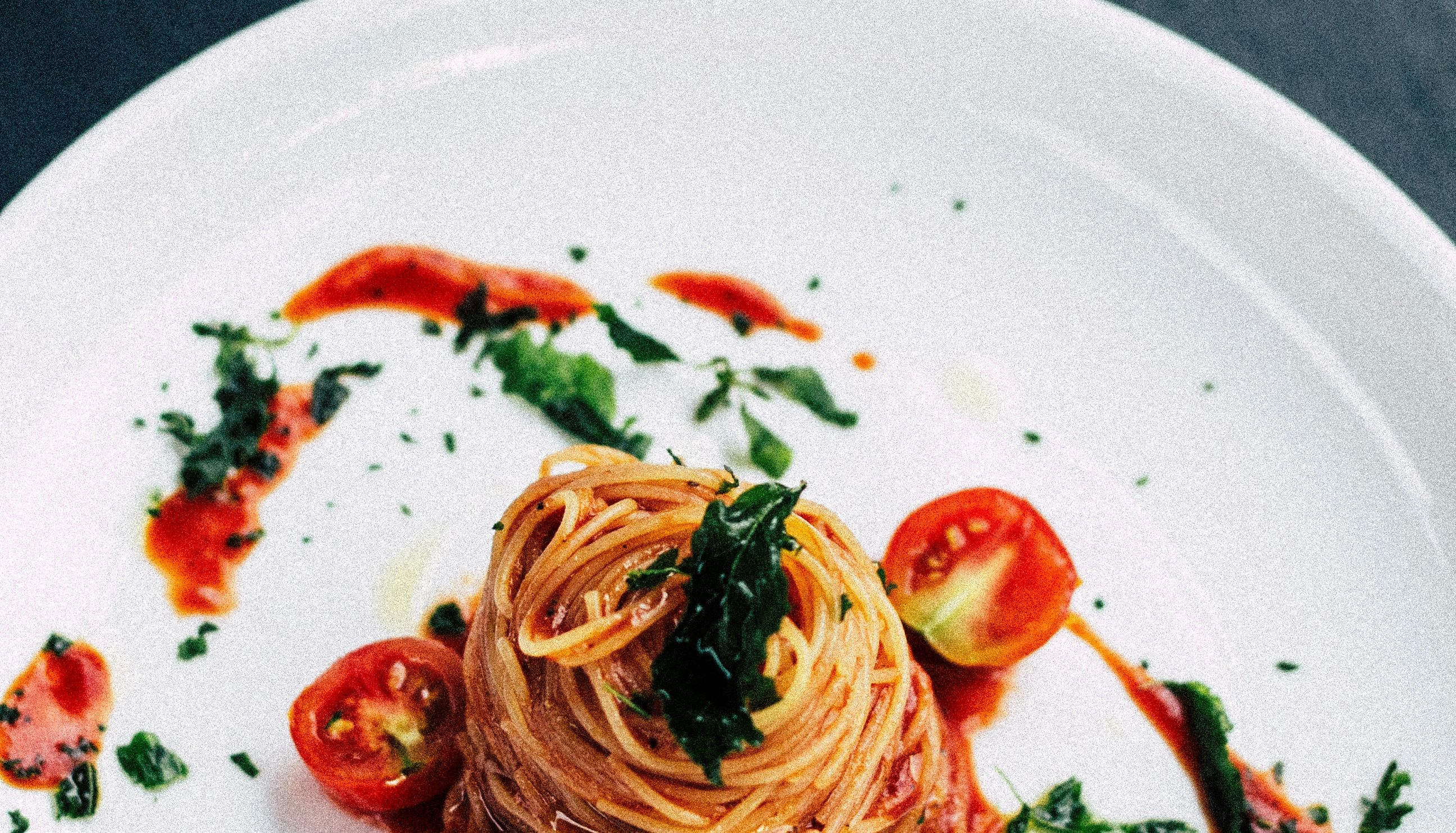 Gourmet spaghetti with tomato sauce and cherry tomatoes on a white plate