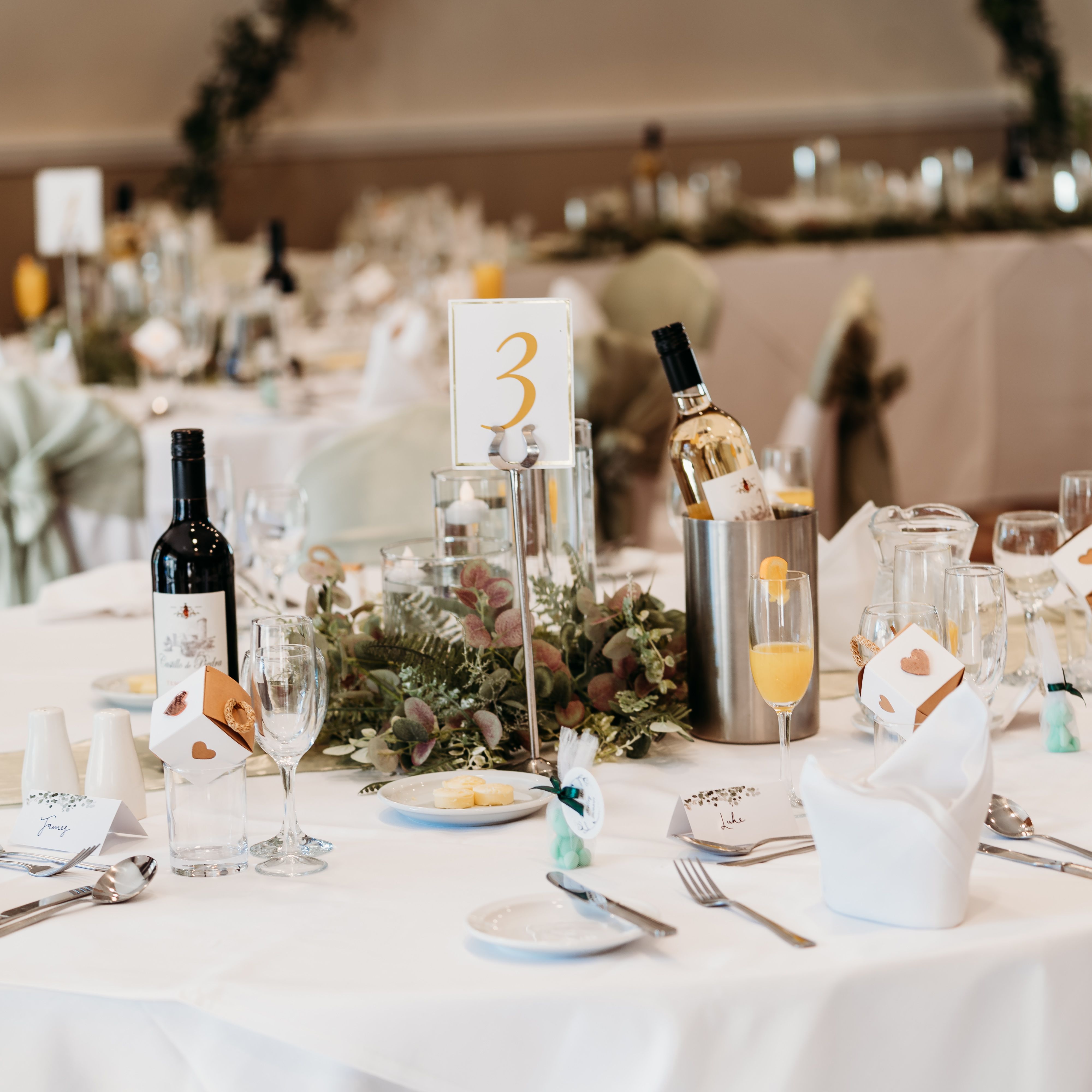 Elegant wedding reception table setting with wine, glasses, and floral centerpiece