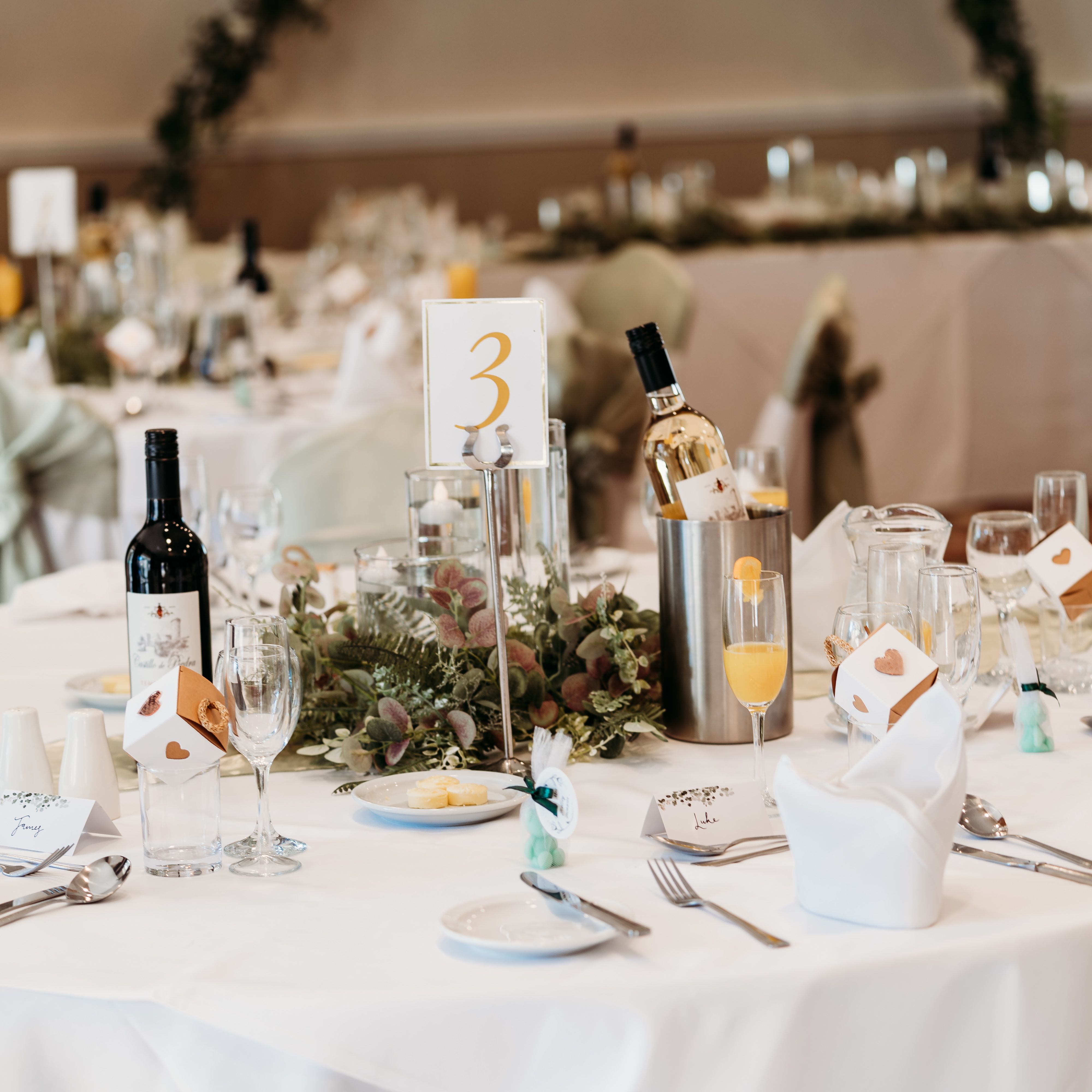 Elegant wedding reception table setting with wine, glasses, and floral centerpiece