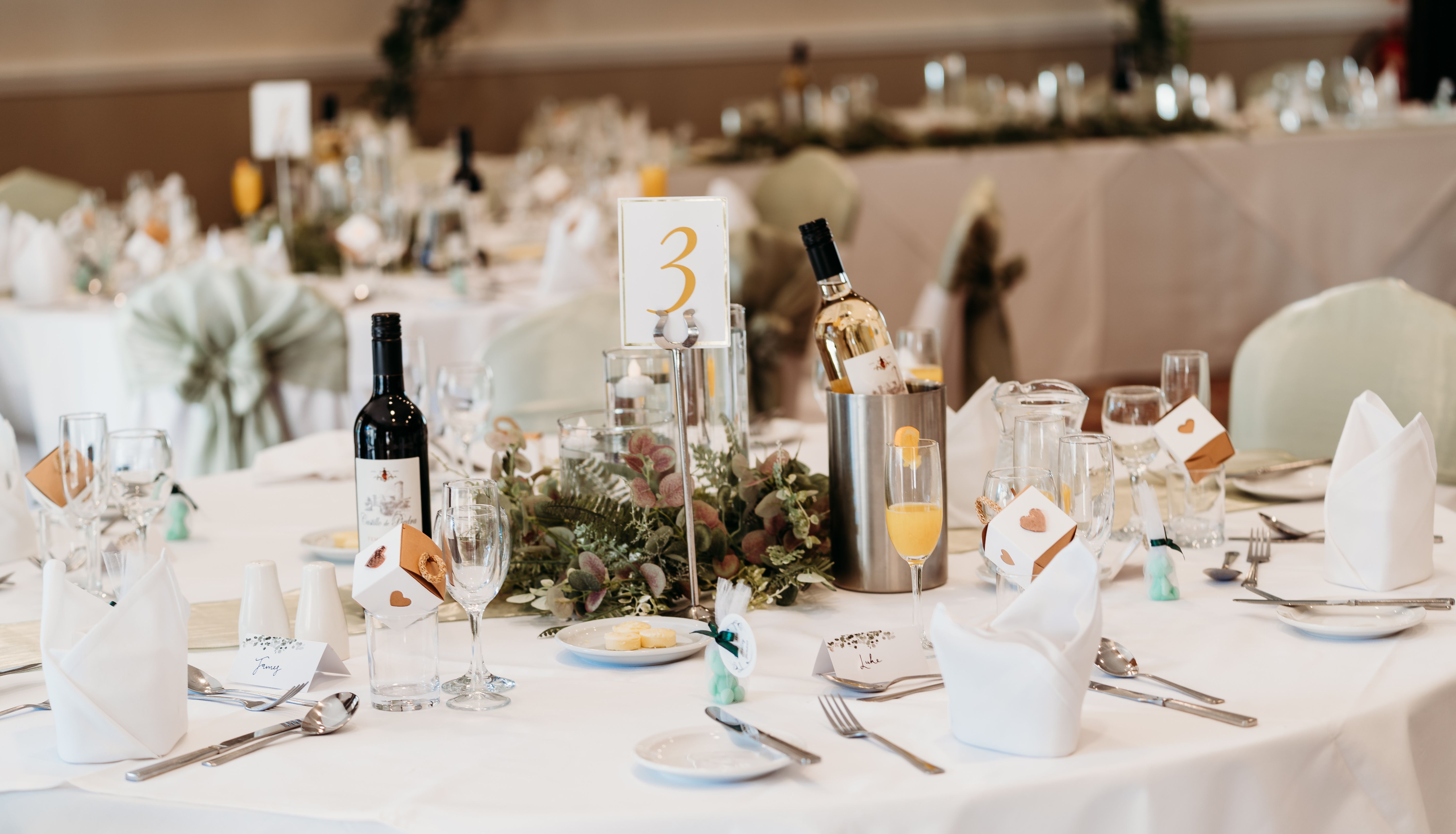 Elegant wedding reception table setting with wine, glasses, and floral centerpiece