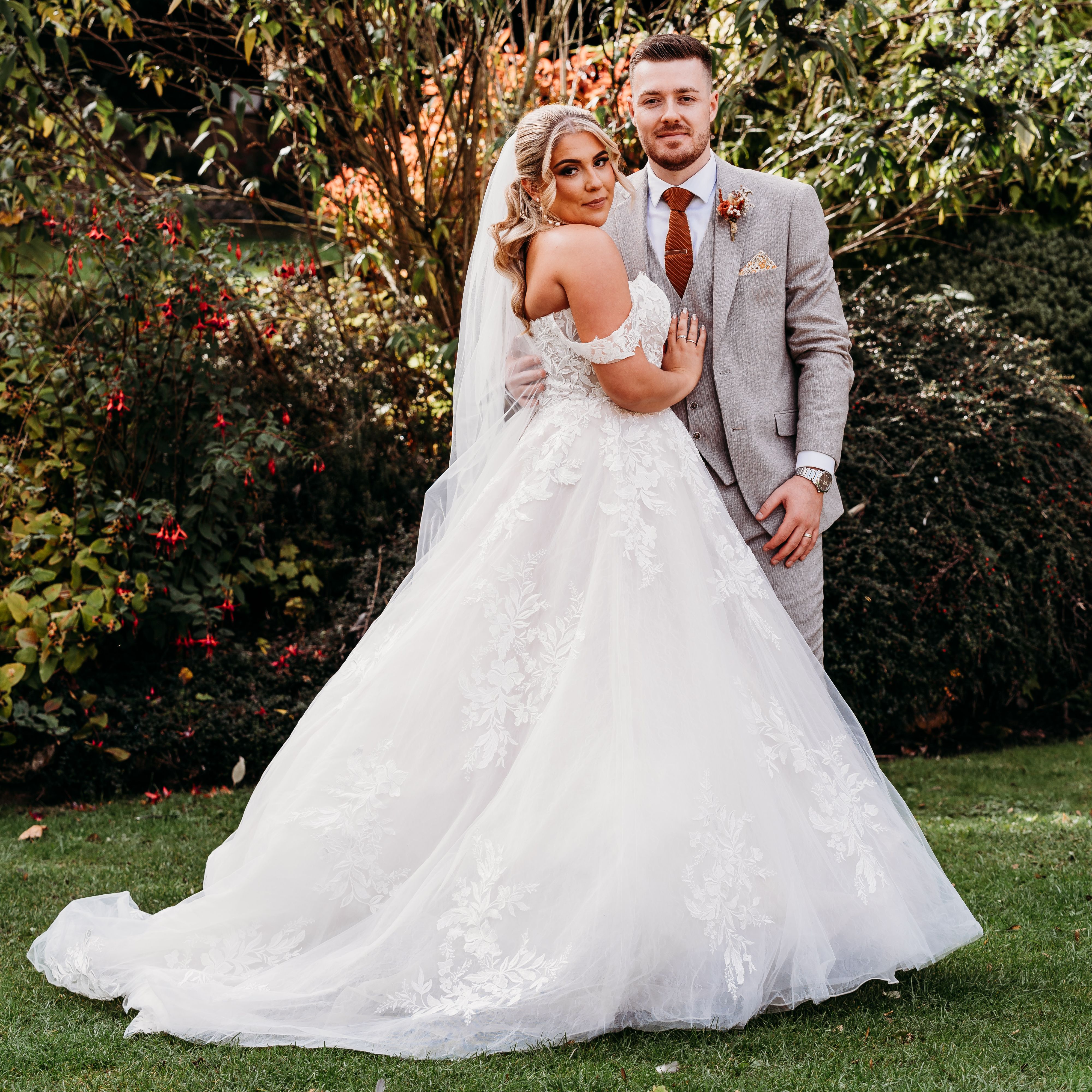 Bride and groom posing outdoors in wedding attire