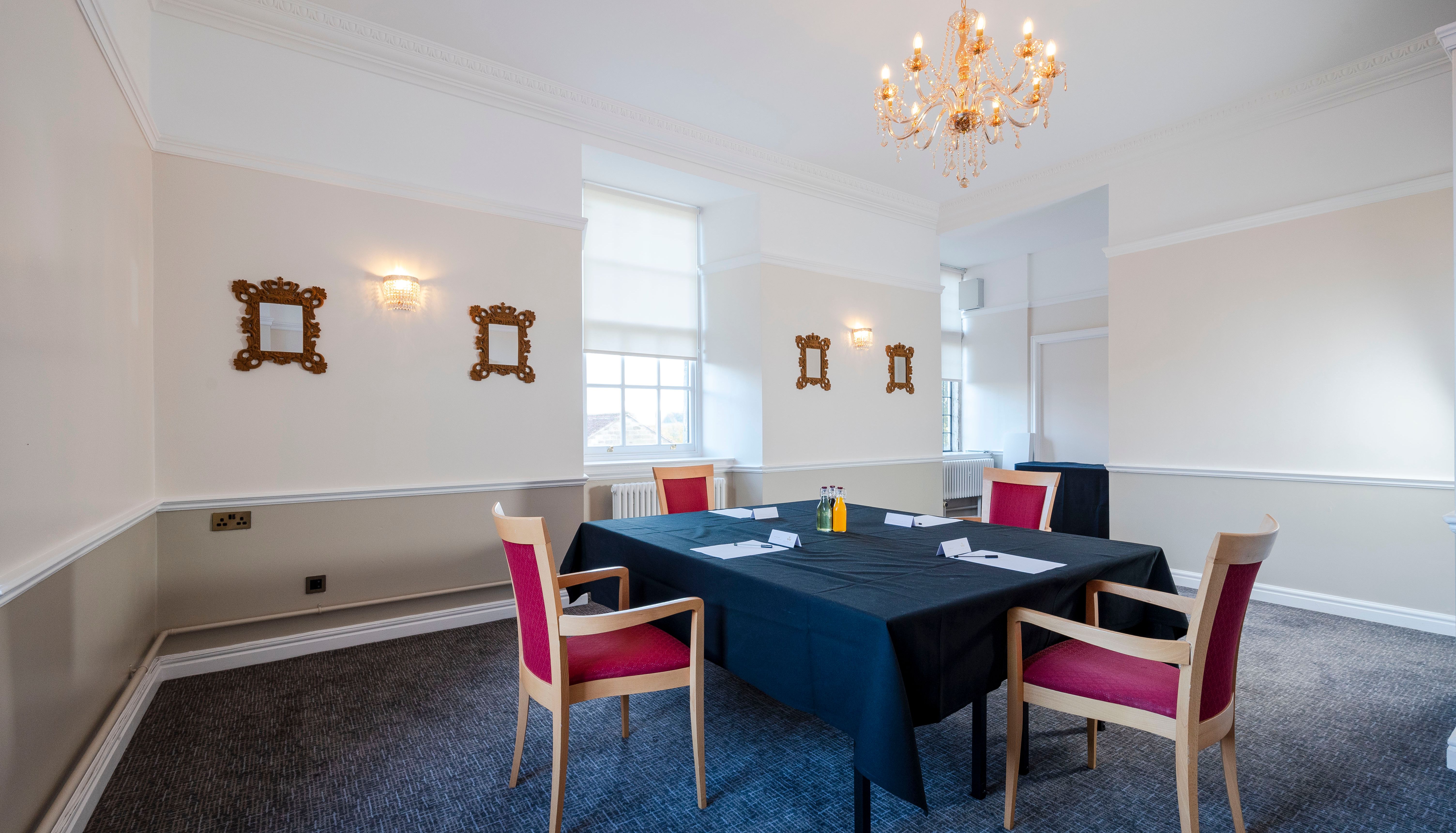 Elegant meeting room with black tablecloth, four red chairs, and chandelier