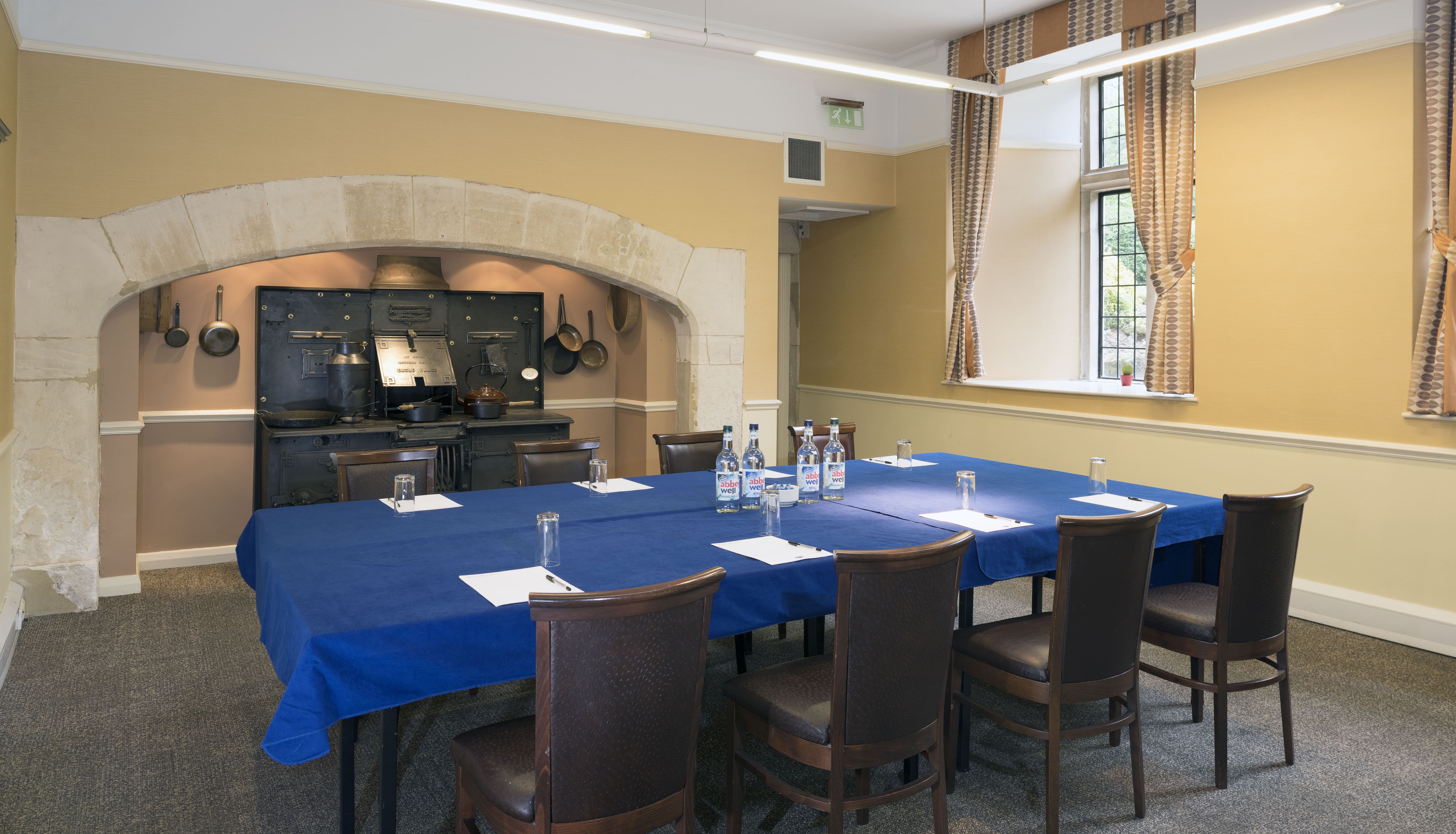 Conference room with a blue tablecloth, chairs, and old-fashioned cooking range in the background
