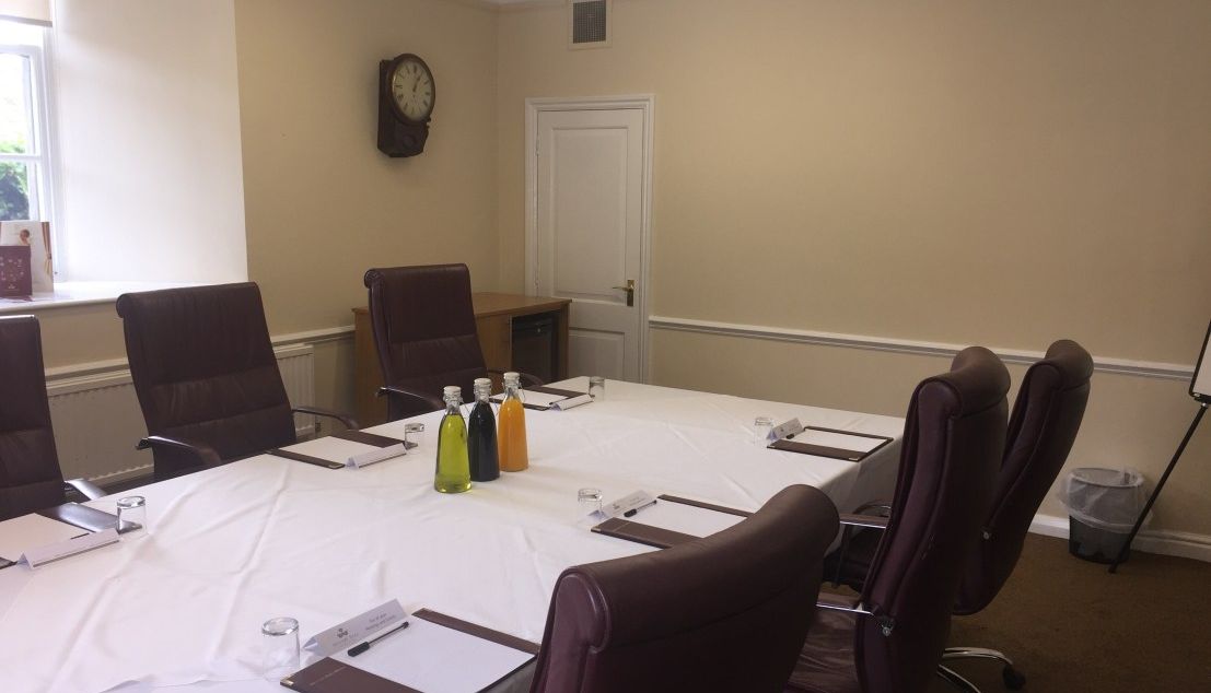 Boardroom setup with chairs, table, bottles, and paperwork