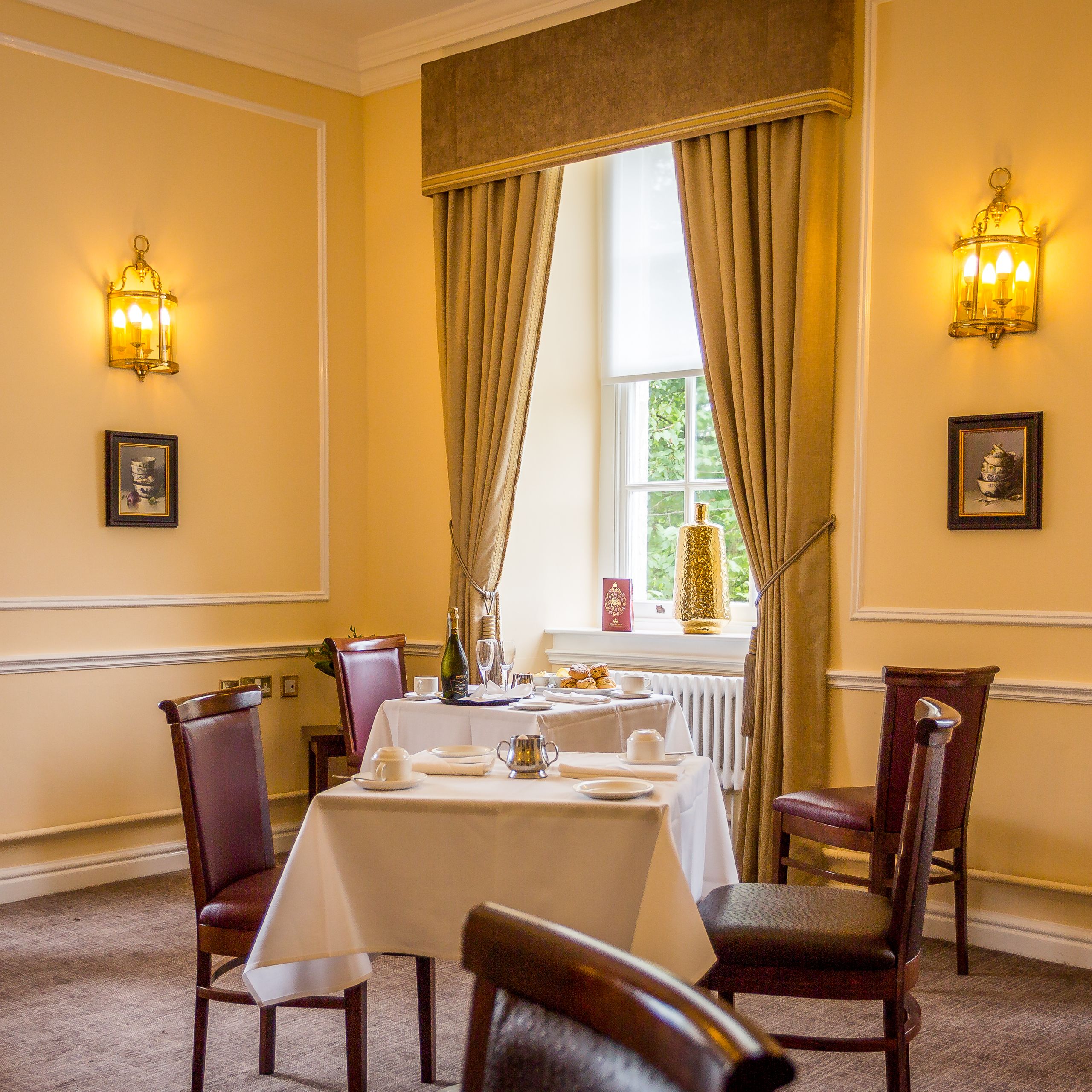 Elegant restaurant dining room with tables and chairs, draped windows, and warm lighting