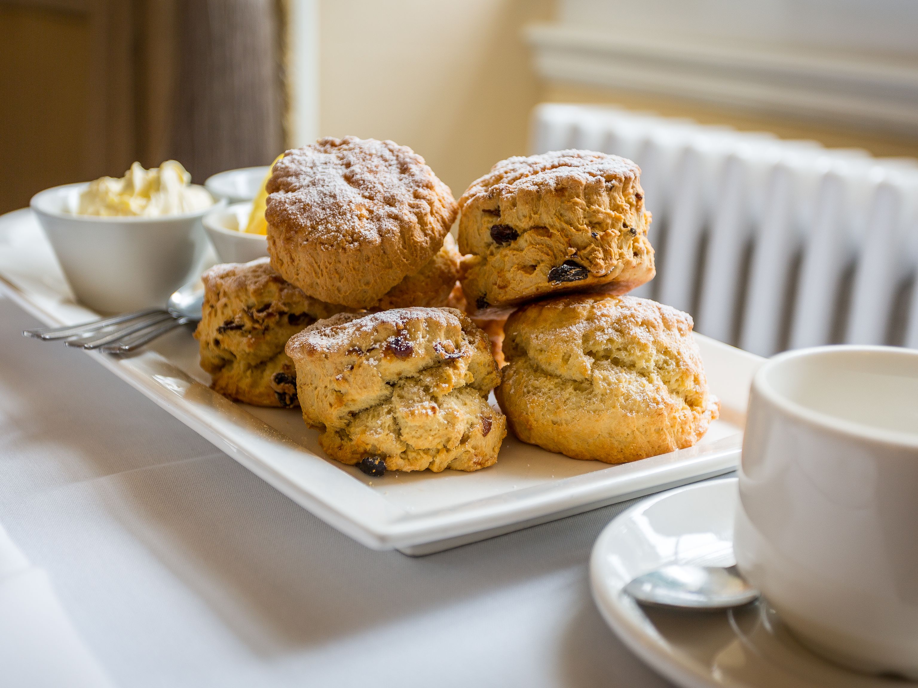 Plate of scones with clotted cream and tea on a table