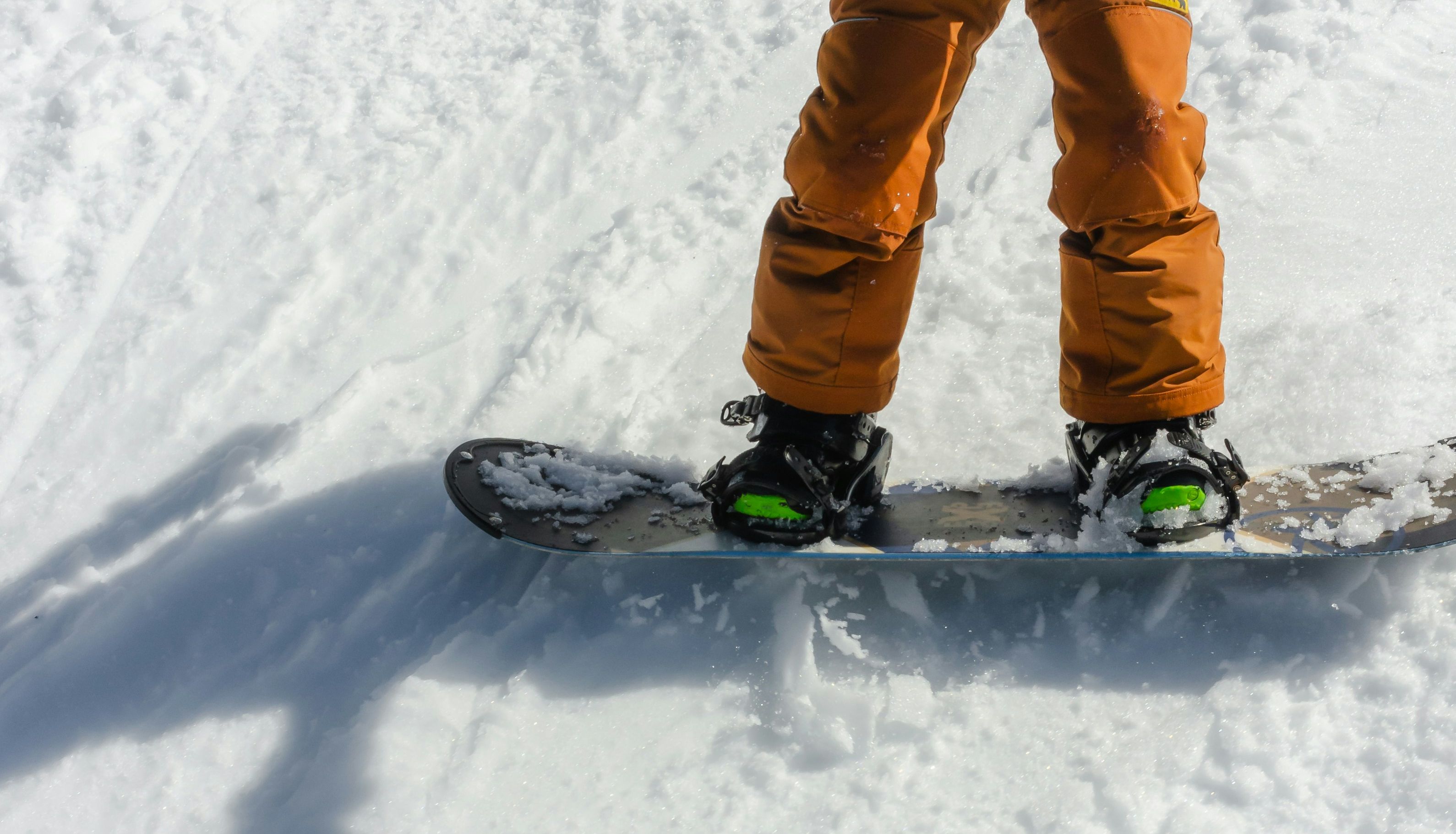 Children snowboarding on a snowy slope, dressed in winter gear.