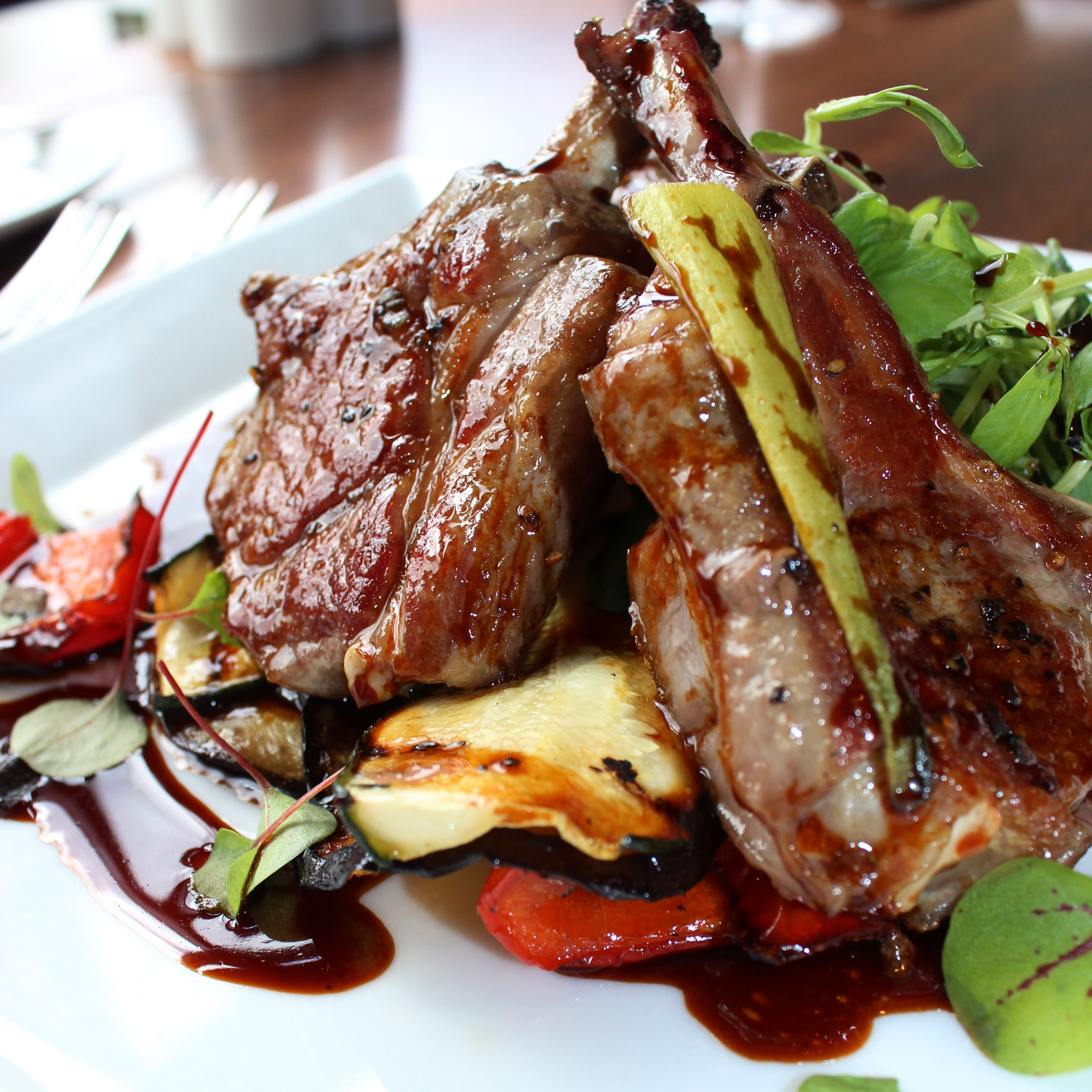 Plated rack of lamb with grilled vegetables and sauce garnish