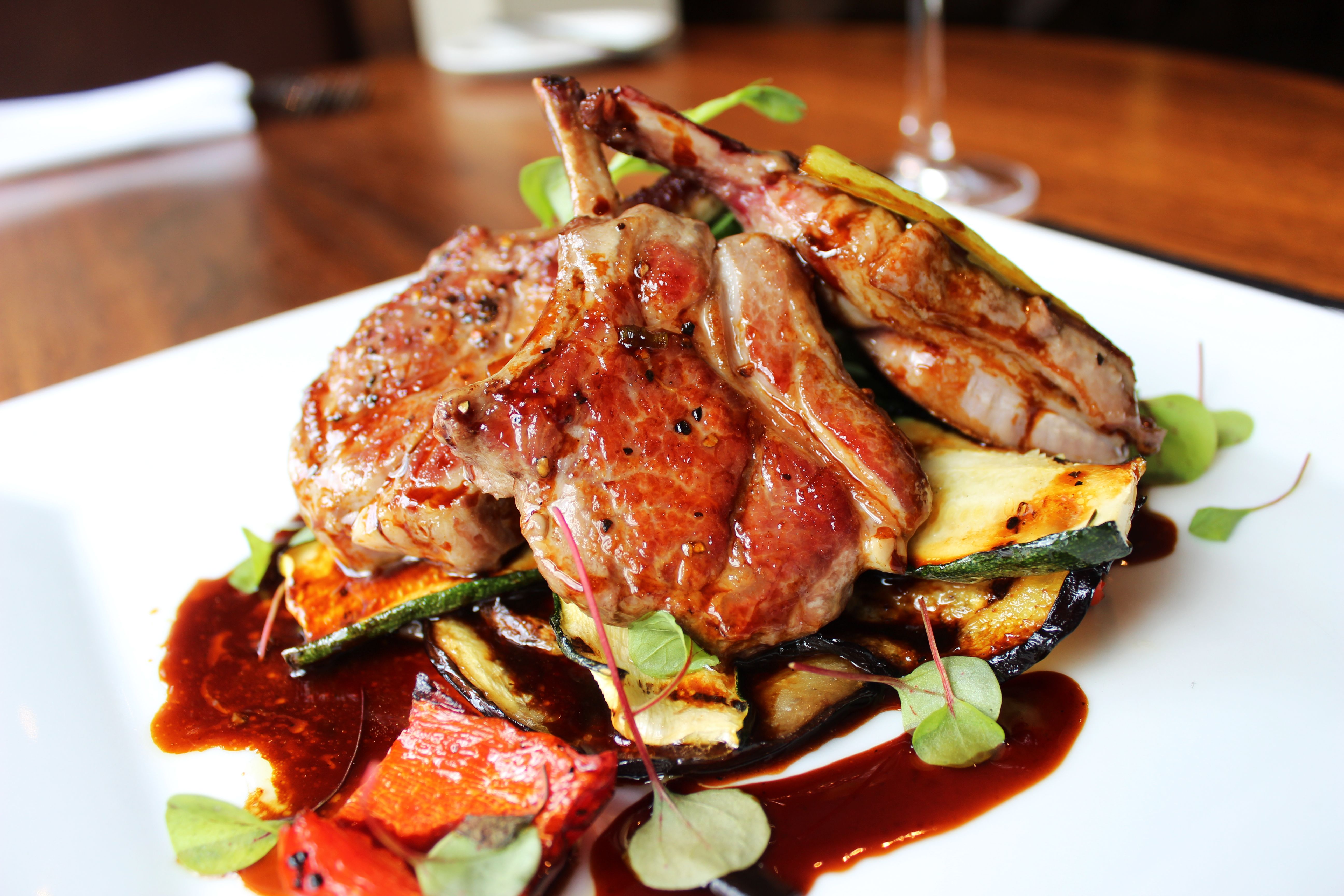 Grilled lamb chops served on a bed of roasted vegetables with sauce