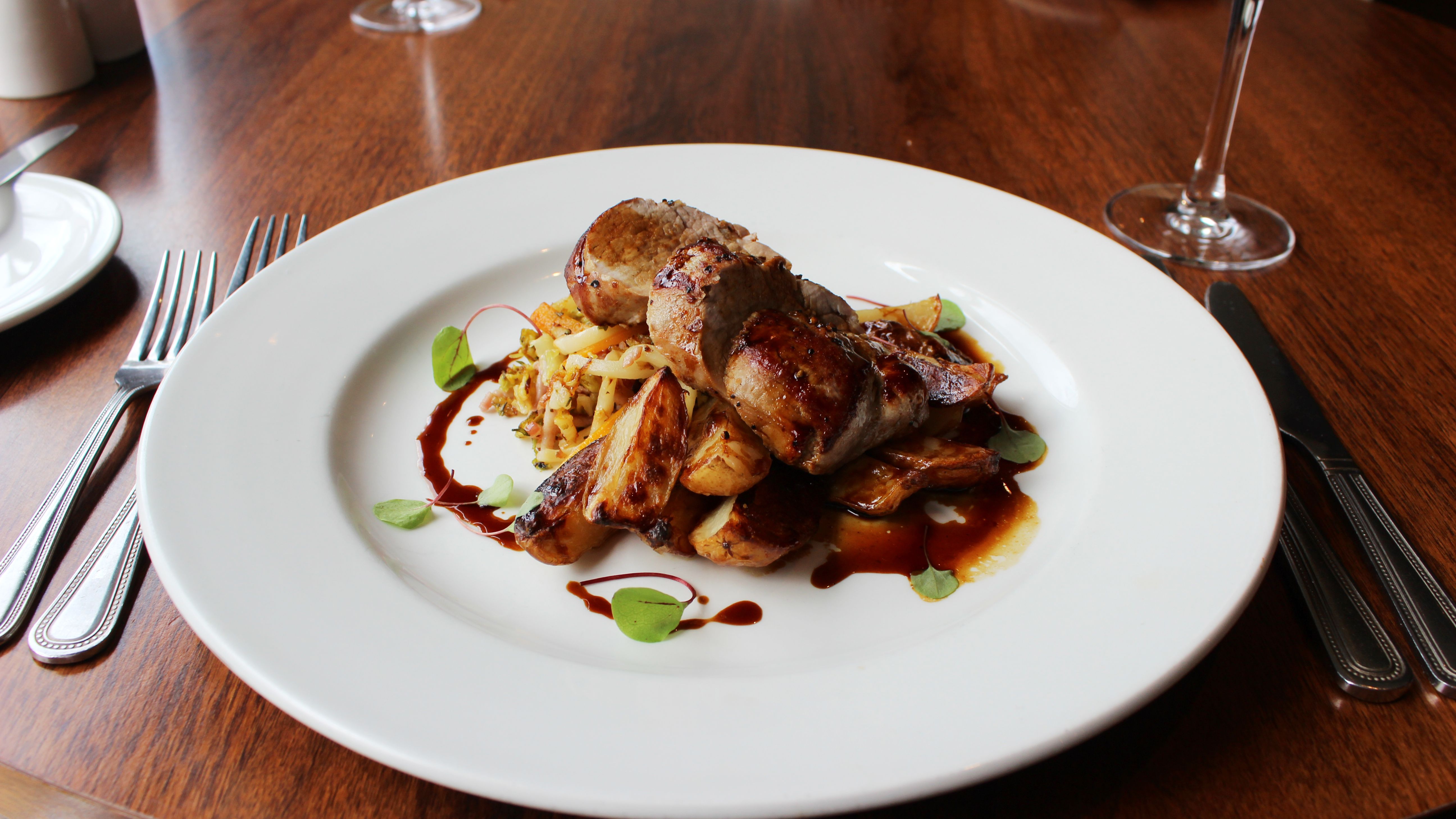 Plated gourmet meat dish with roasted vegetables and sauce on a white plate