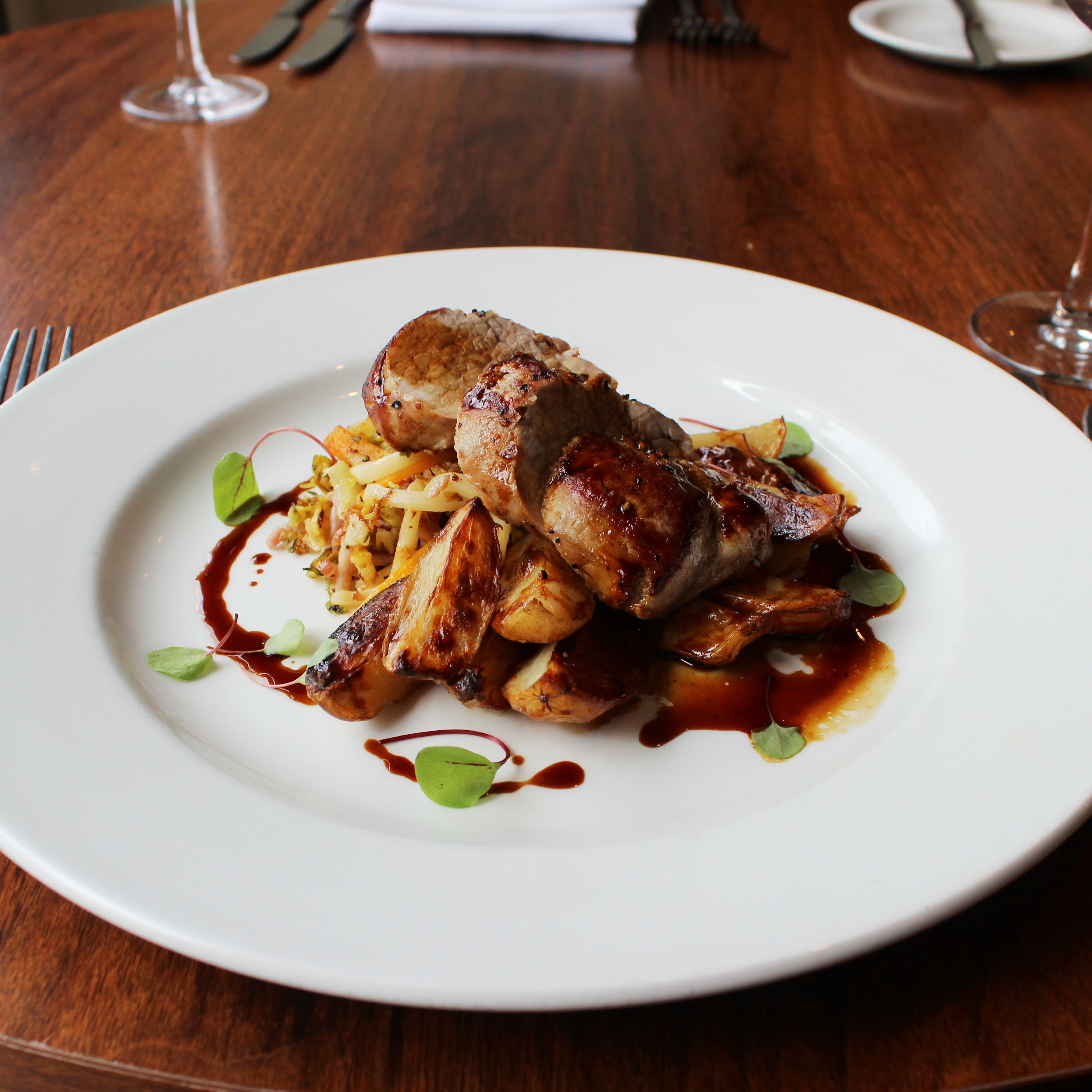 Plated gourmet meat dish with roasted vegetables and sauce on a white plate