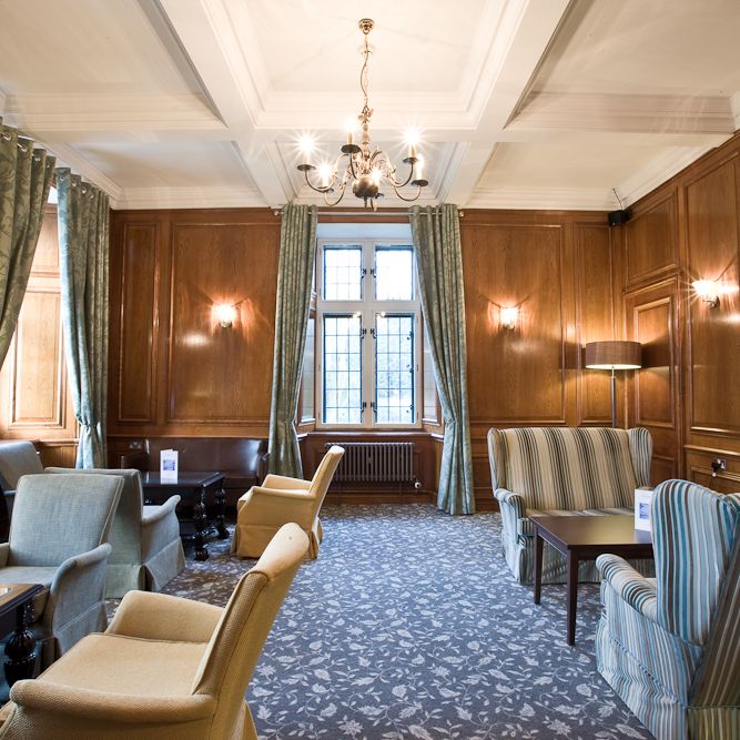Elegant lounge with armchairs, wooden paneling, and chandelier lighting