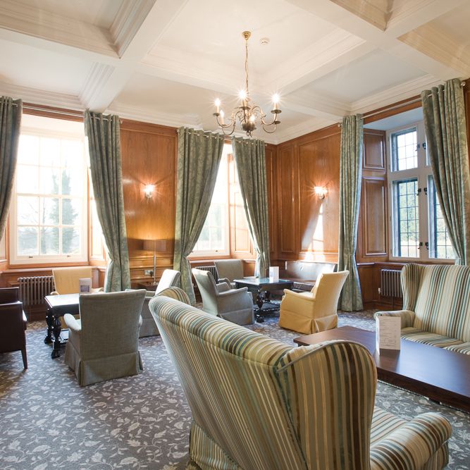 Elegant lounge with striped sofas, armchairs, large windows, and wood paneling