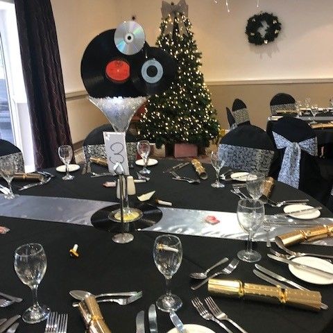Festively decorated dining table with vinyl records centerpiece and Christmas tree in the background