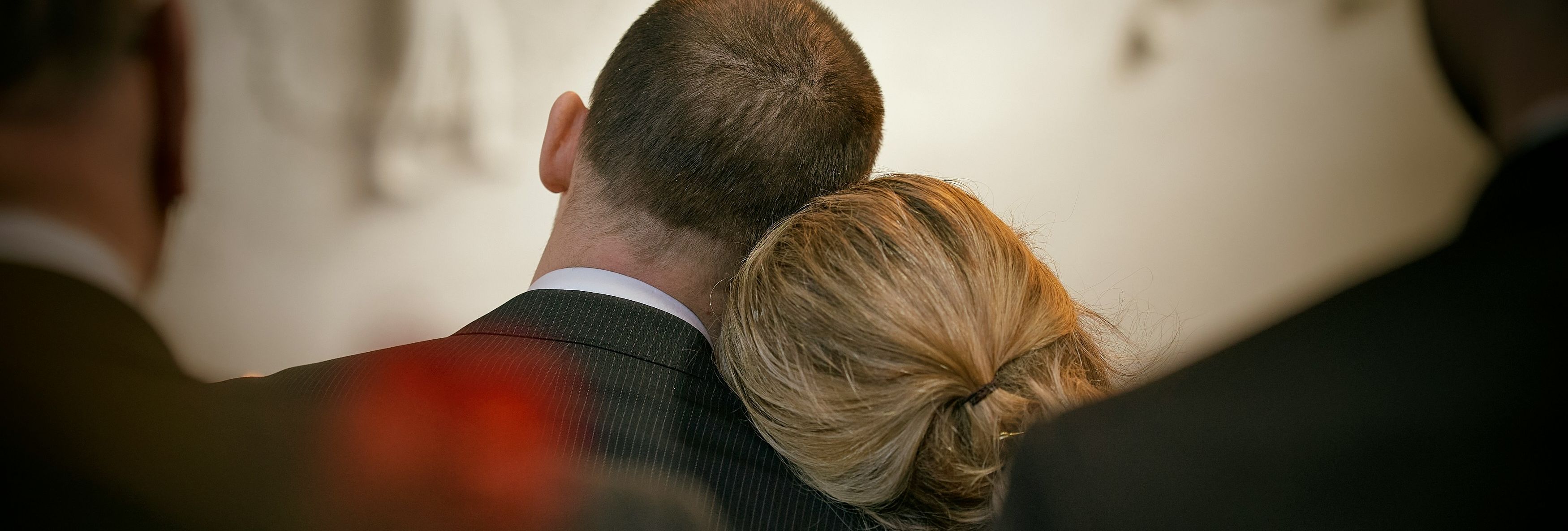 A couple sitting together, with the woman resting her head on the man's shoulder in a comforting gesture.