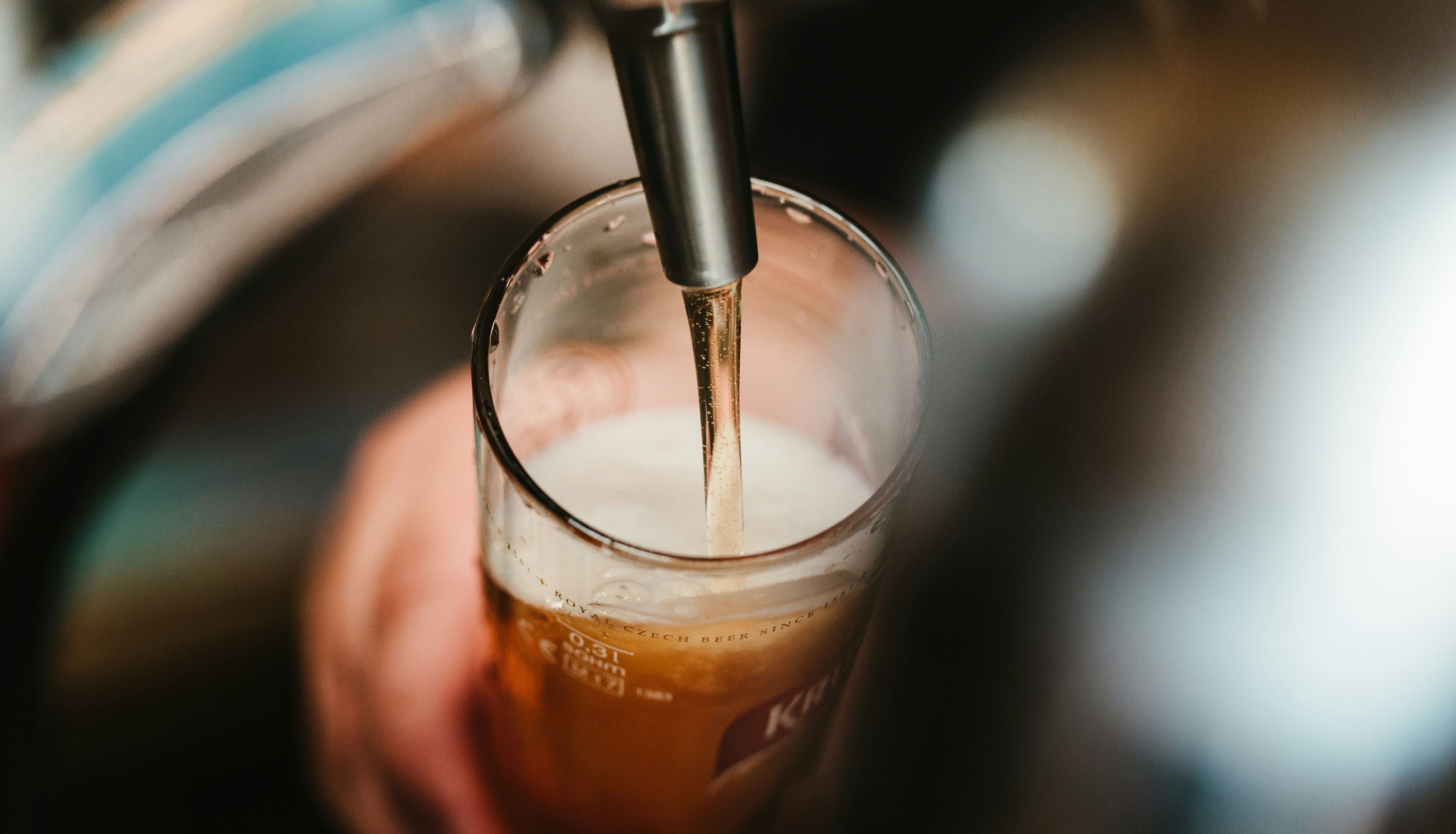 Draft beer being poured into a glass from a tap.