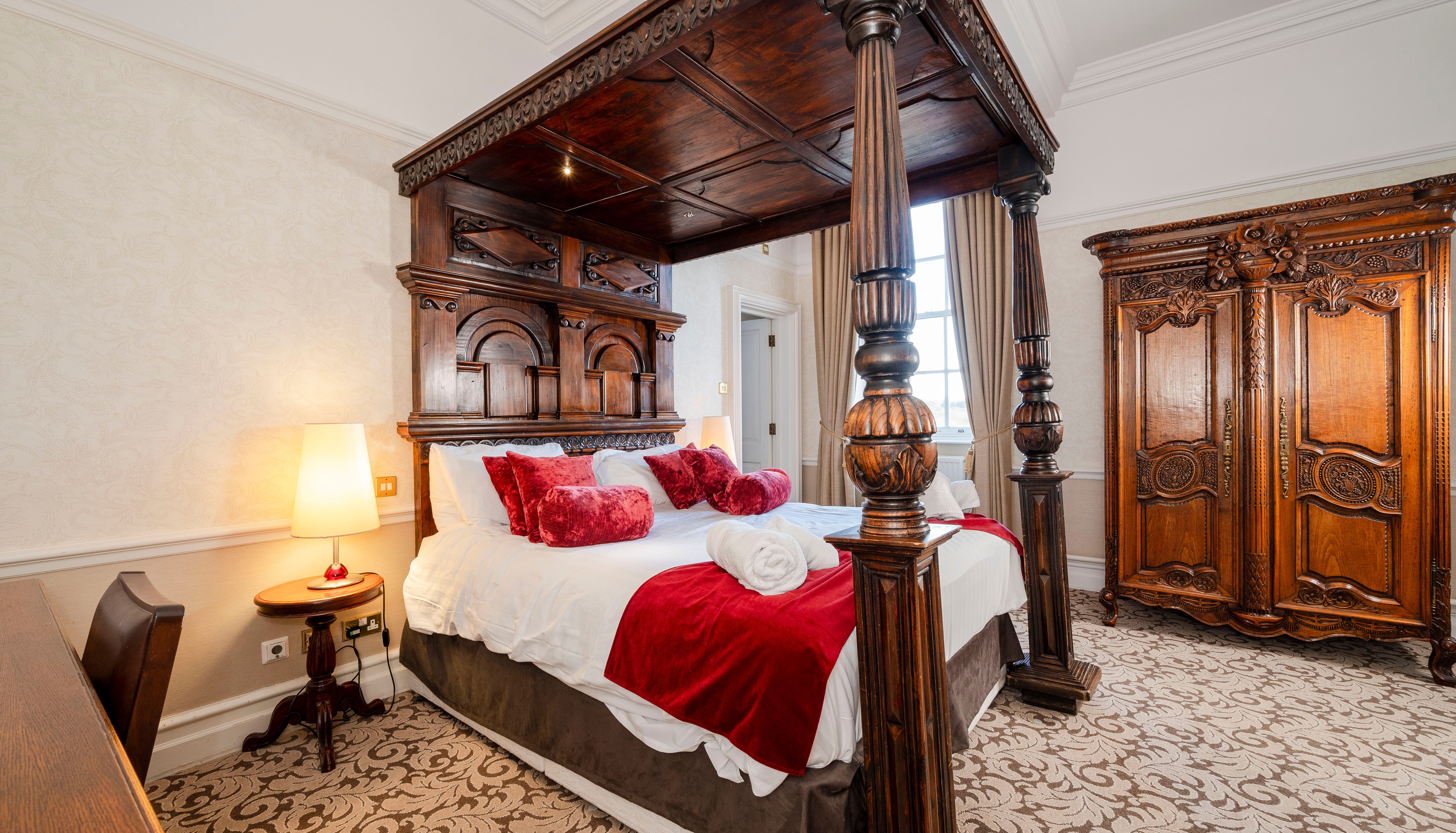 Elegant bedroom with a large wooden four-poster bed and ornate wooden wardrobe