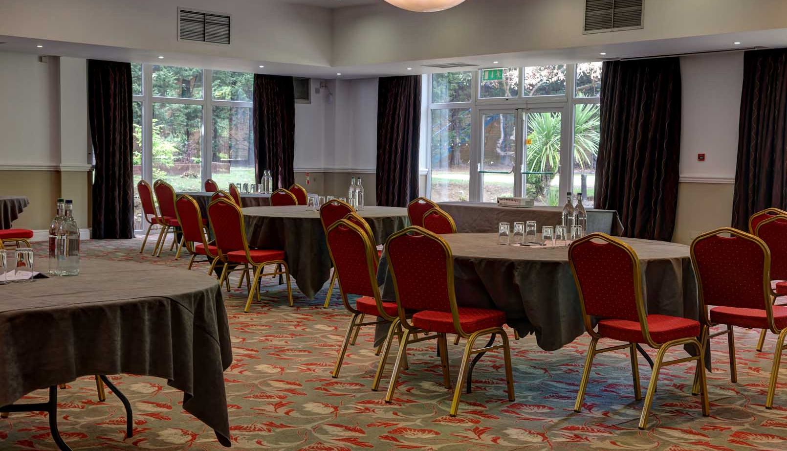 Empty conference room with round tables and red chairs arranged for a meeting