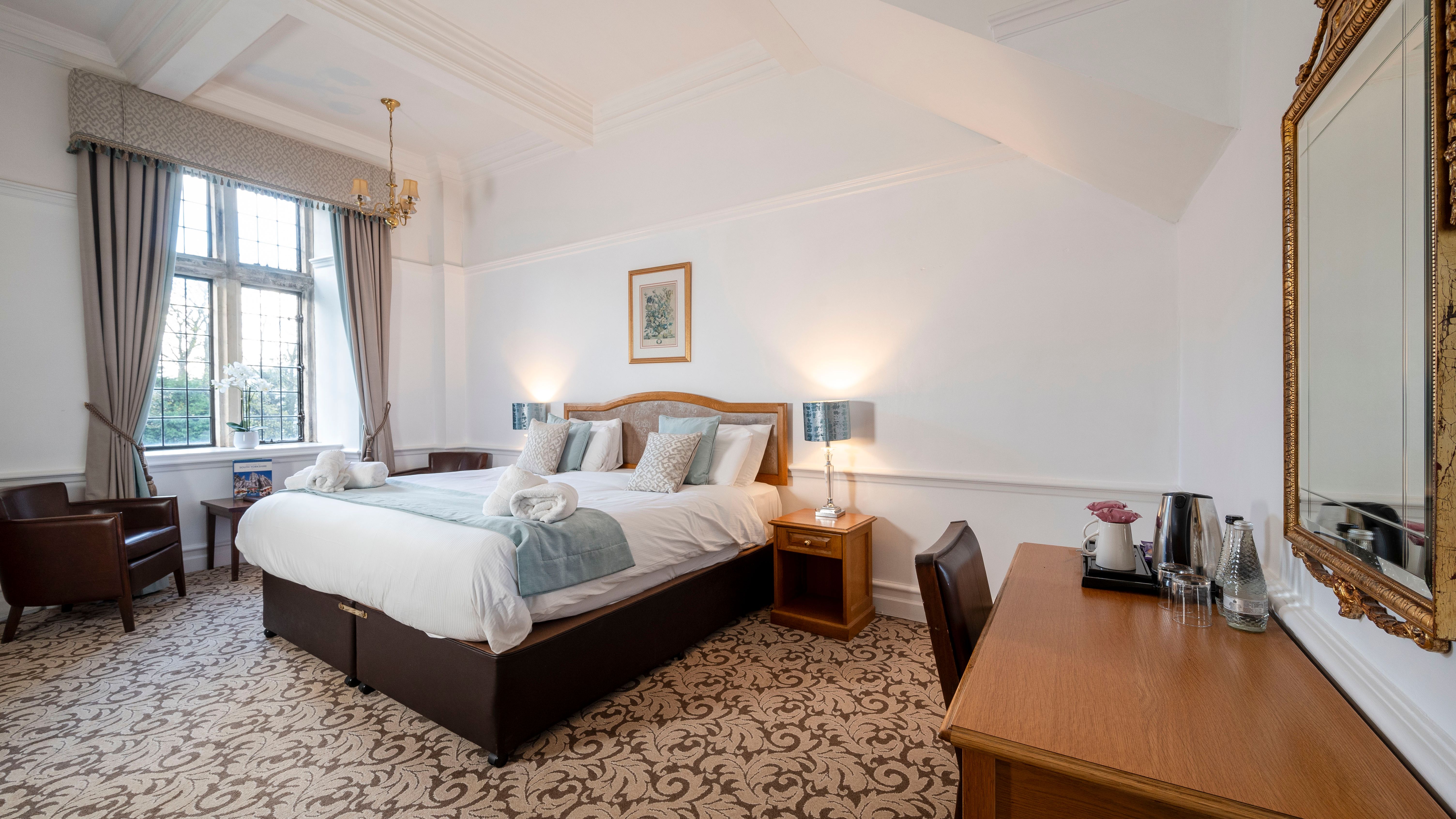 Elegant hotel room with a large bed, wooden furniture, and patterned carpet