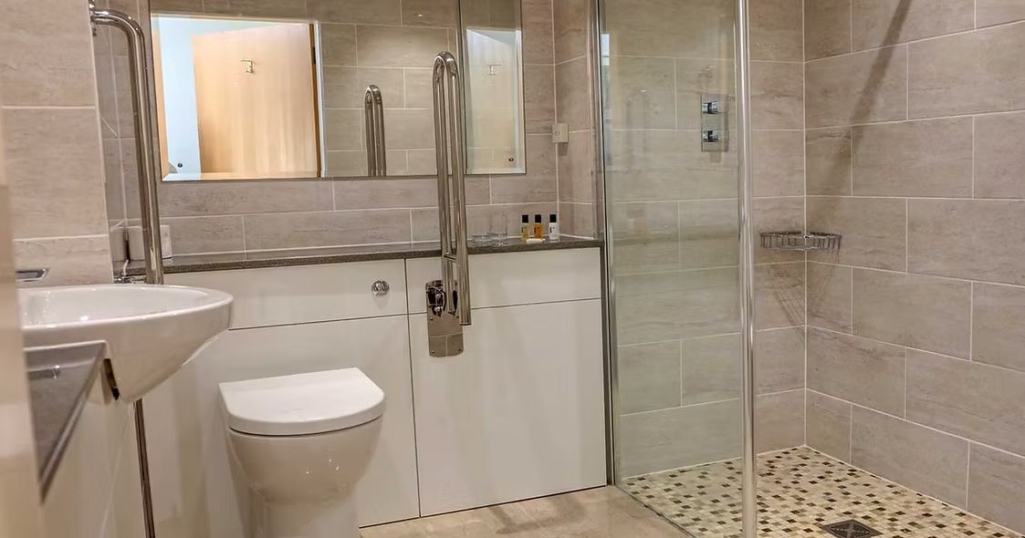 Accessible modern bathroom with walk-in shower, toilet, and large mirror
