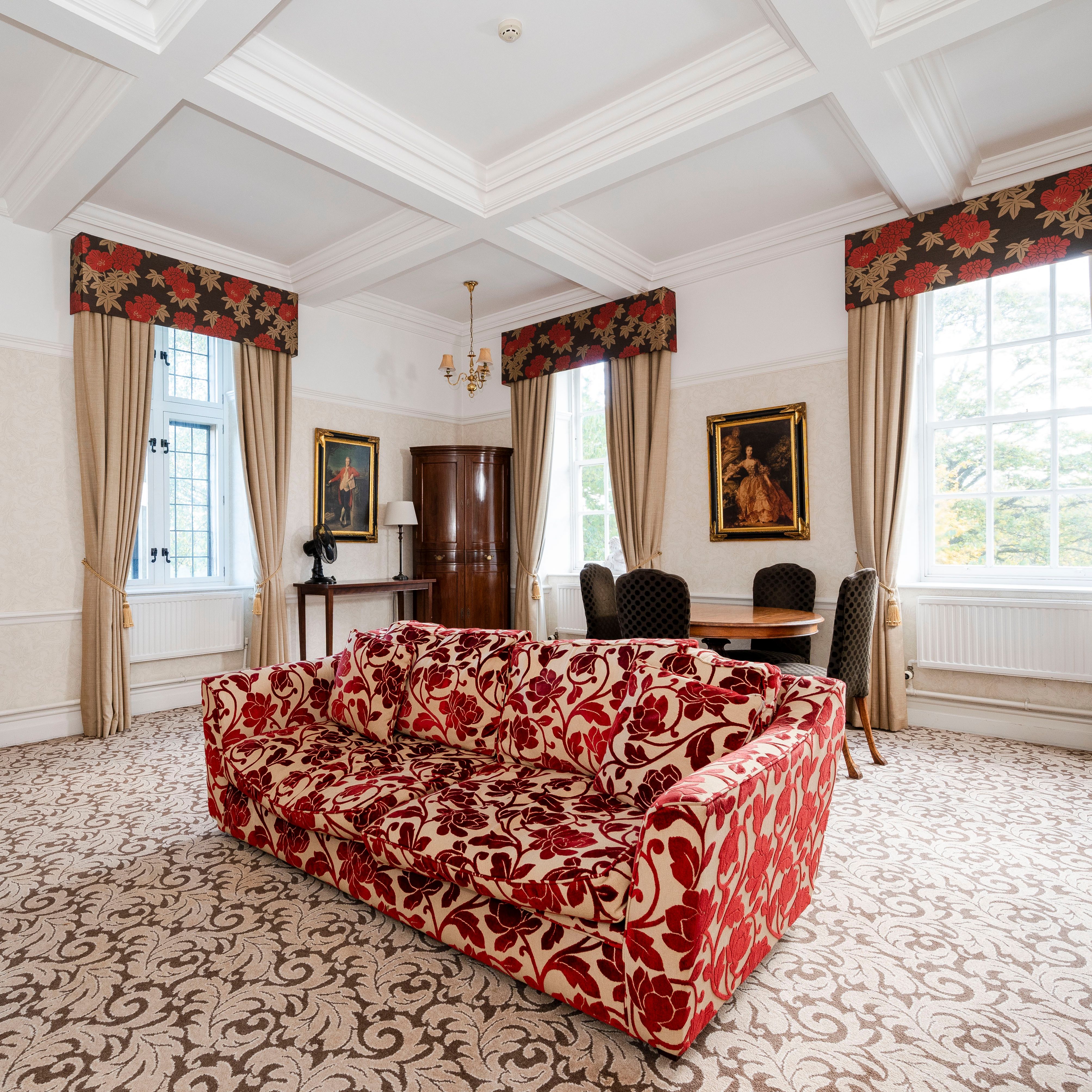 Elegant living room with floral-patterned furniture, large windows, and classic decor.