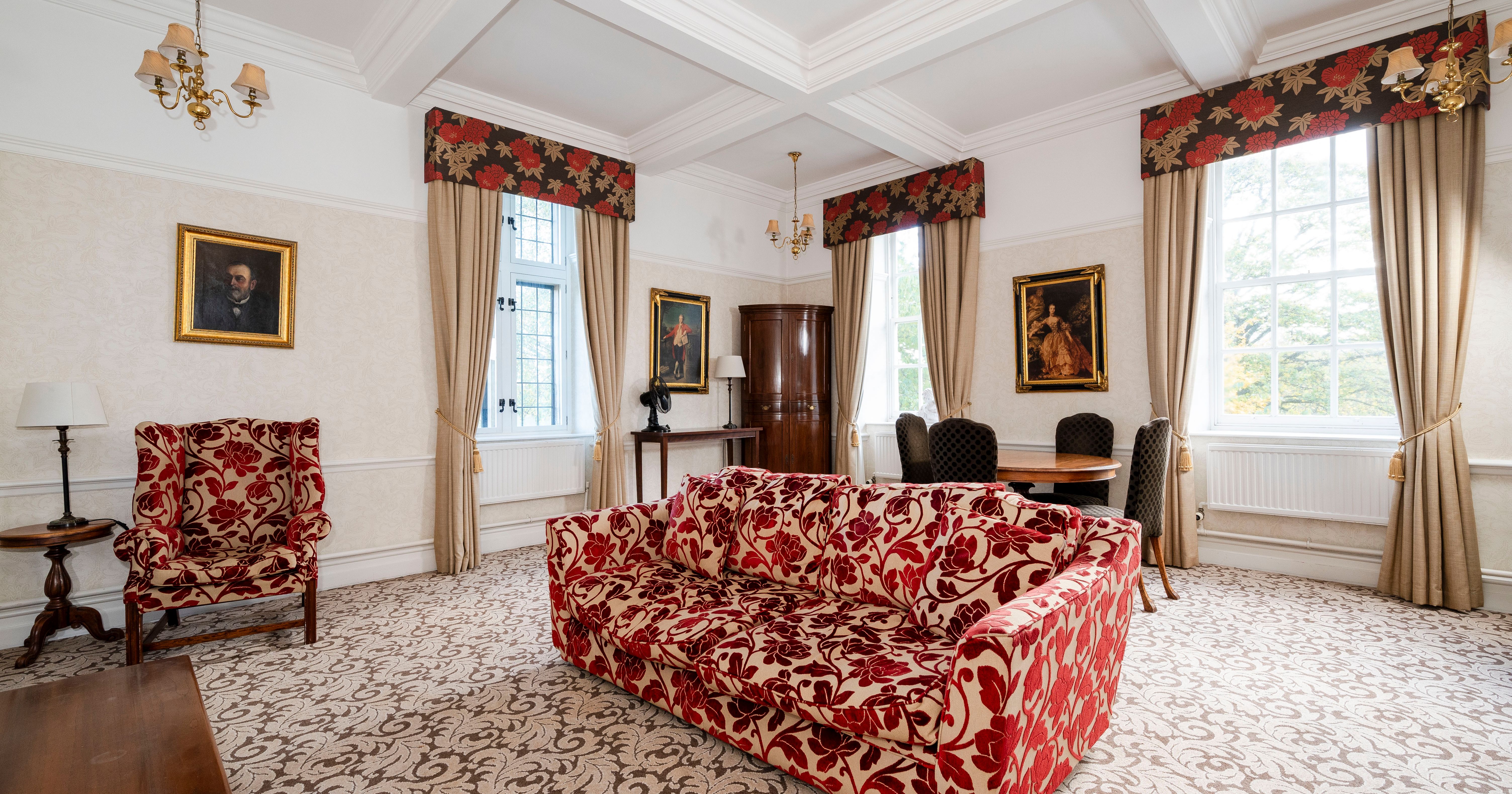 Elegant living room with floral-patterned furniture, large windows, and classic decor.