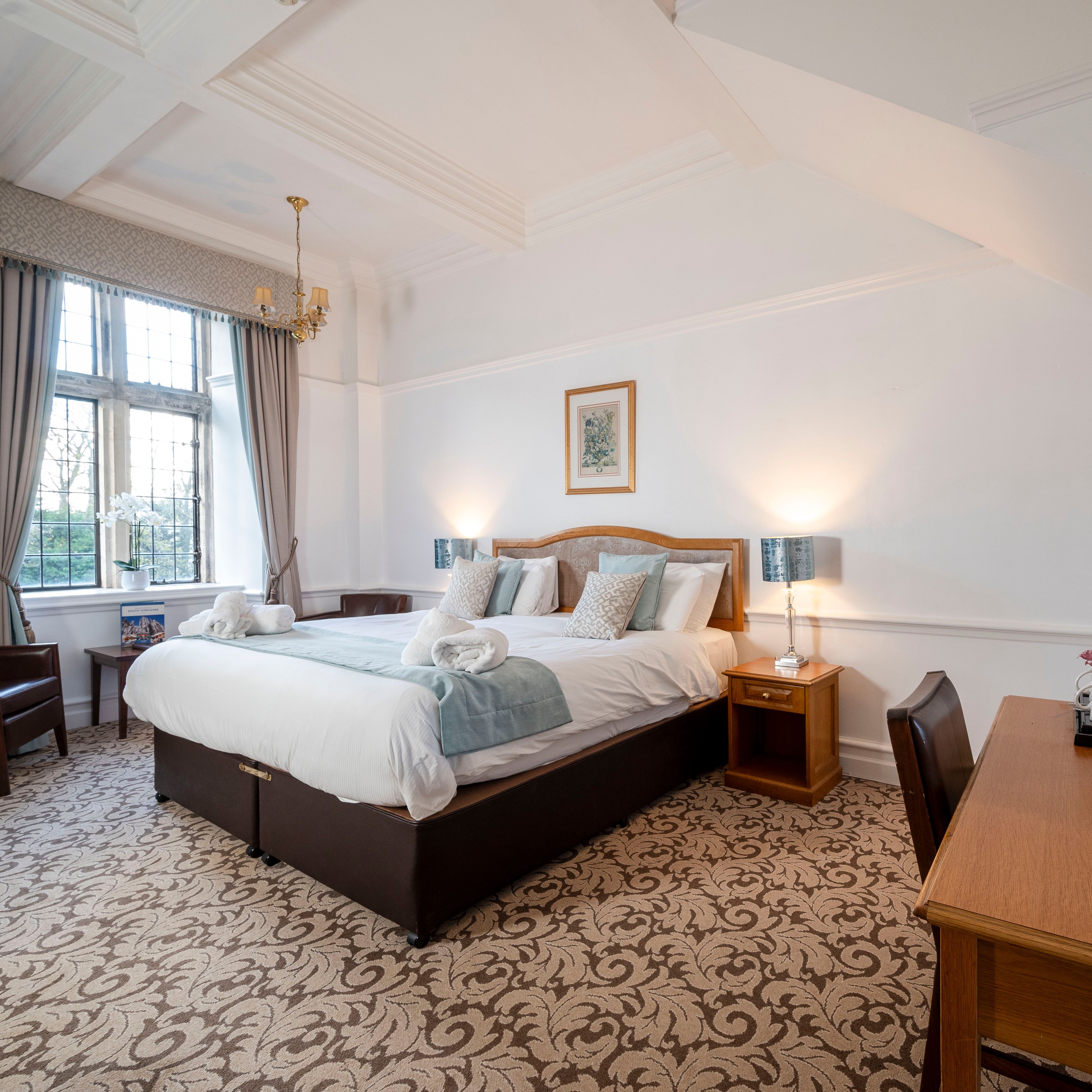 Elegant hotel room with a large bed, wooden furniture, and a window with curtains.