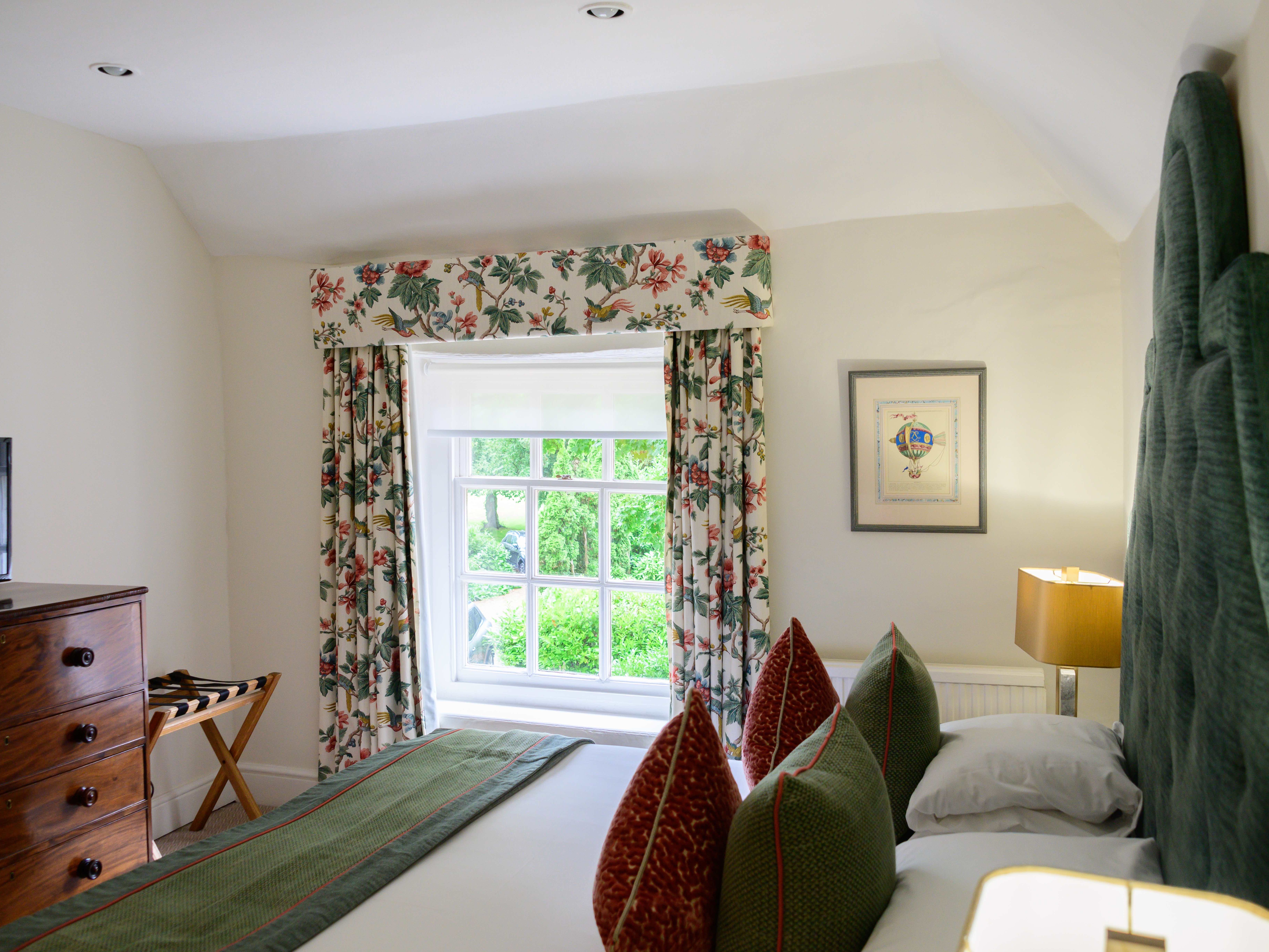 Brightly lit cozy bedroom with green accents and floral curtains