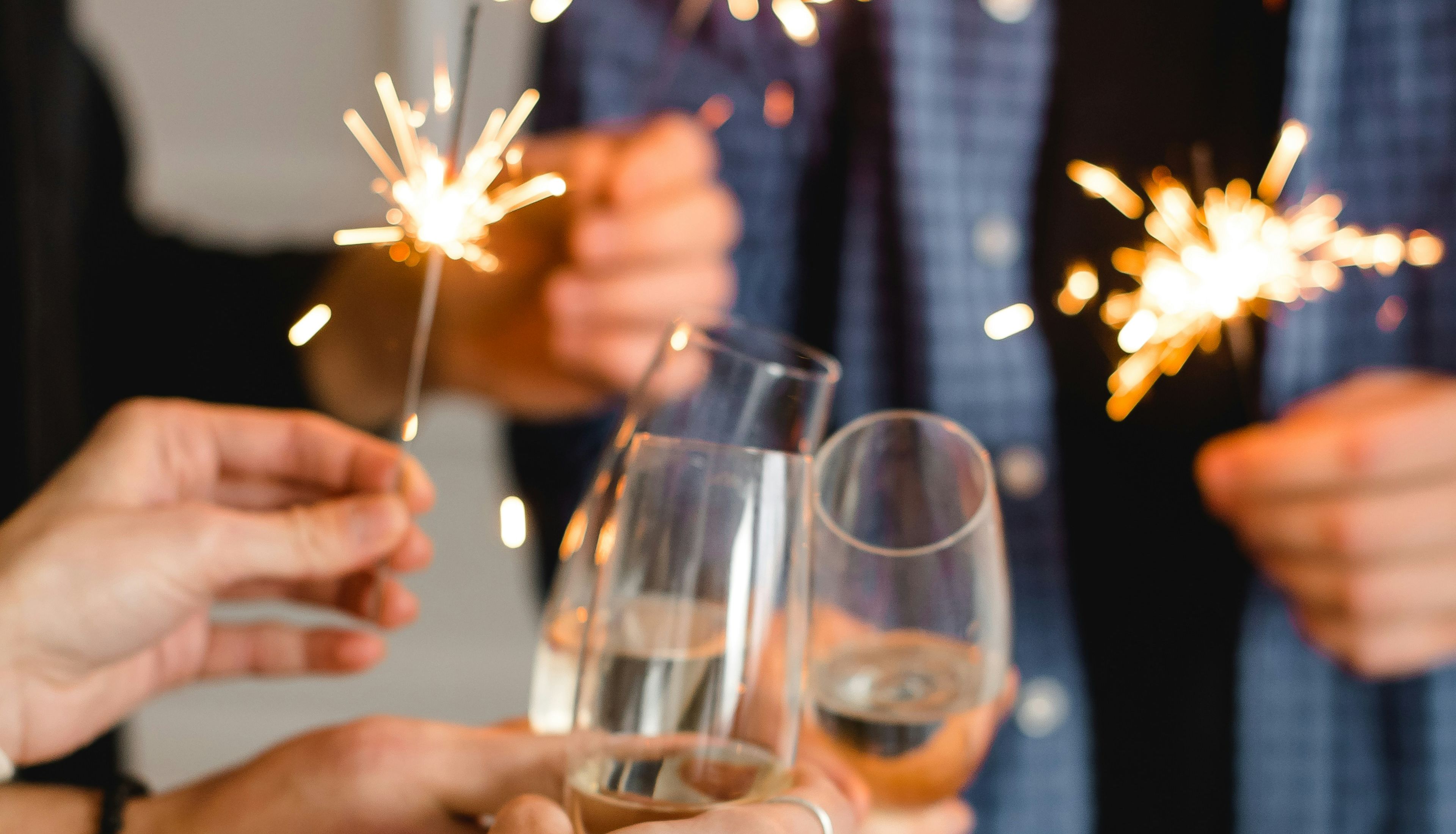 People holding sparklers and clinking champagne glasses in celebration