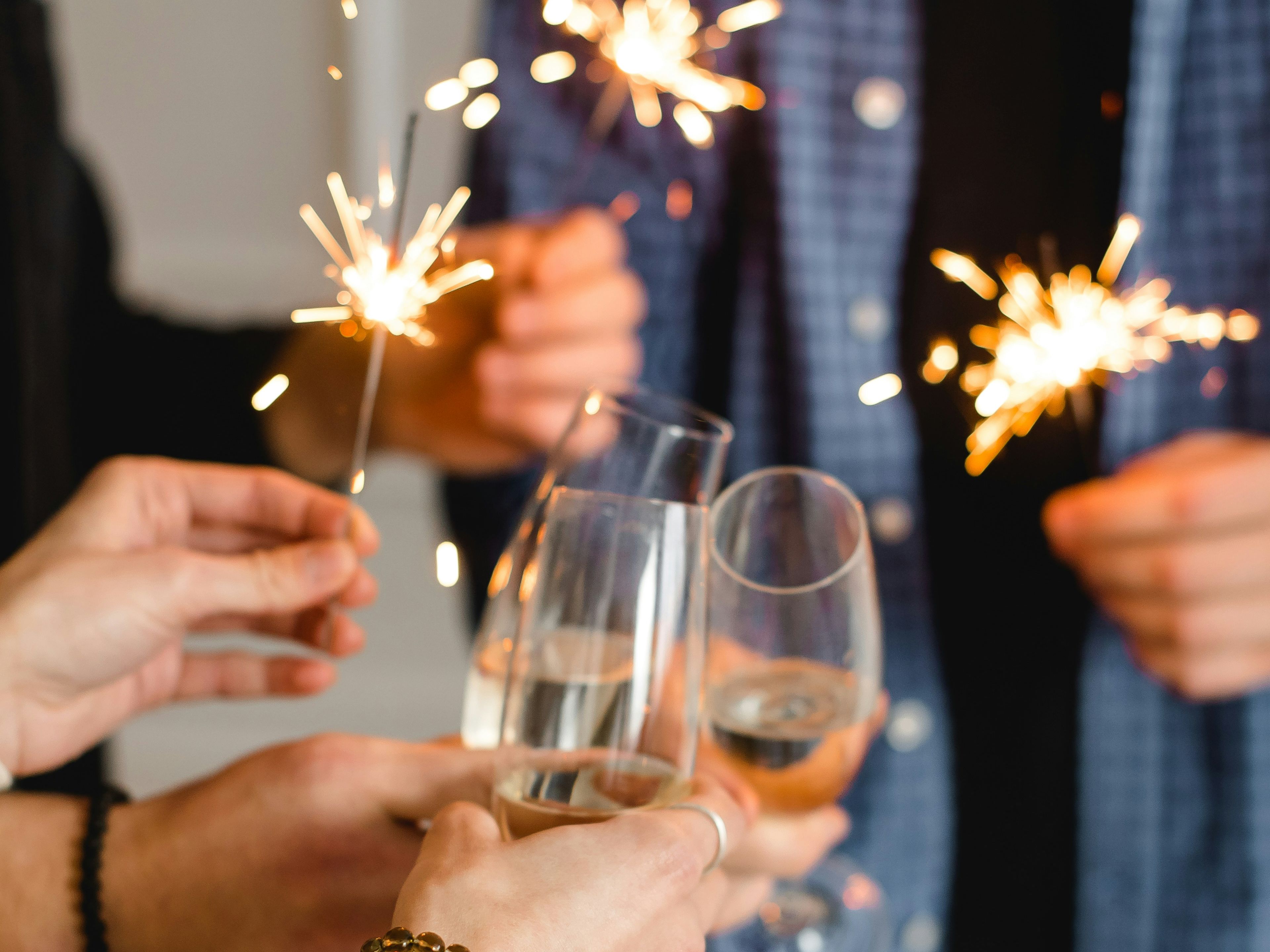 People holding sparklers and clinking champagne glasses in celebration