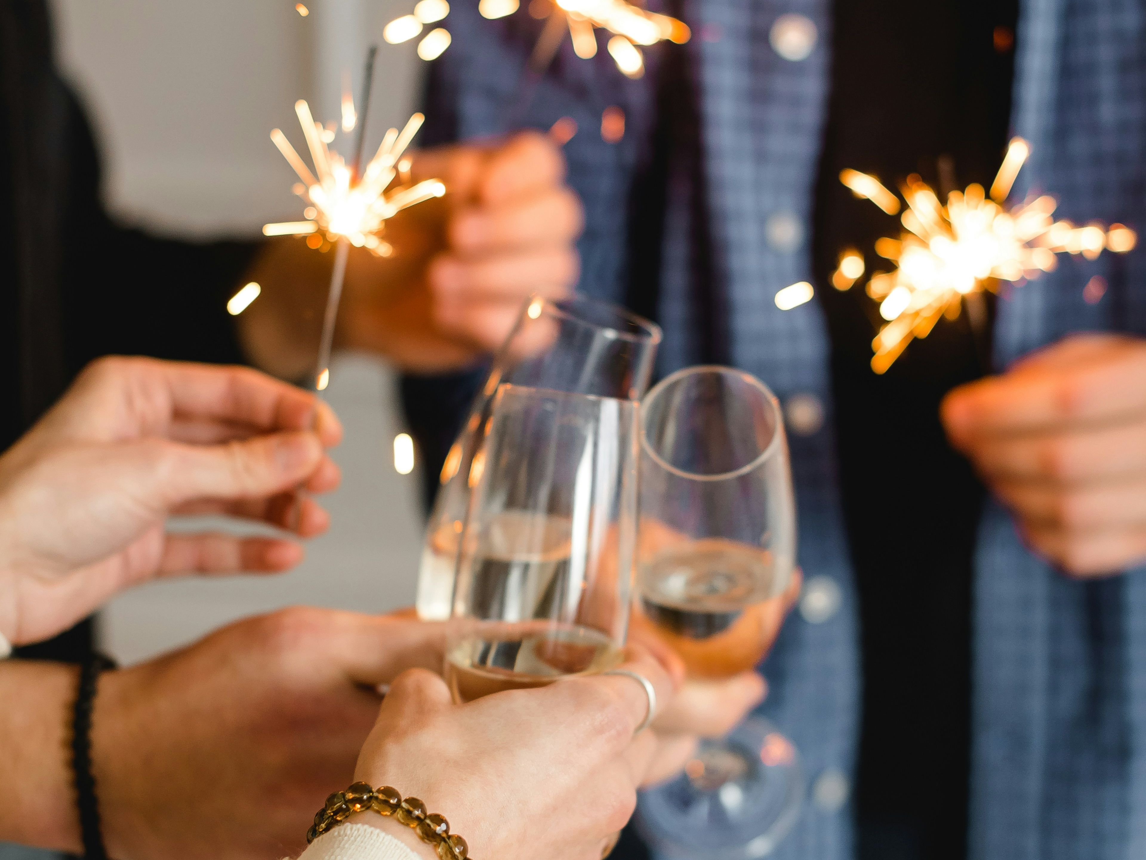 People holding sparklers and clinking champagne glasses in celebration