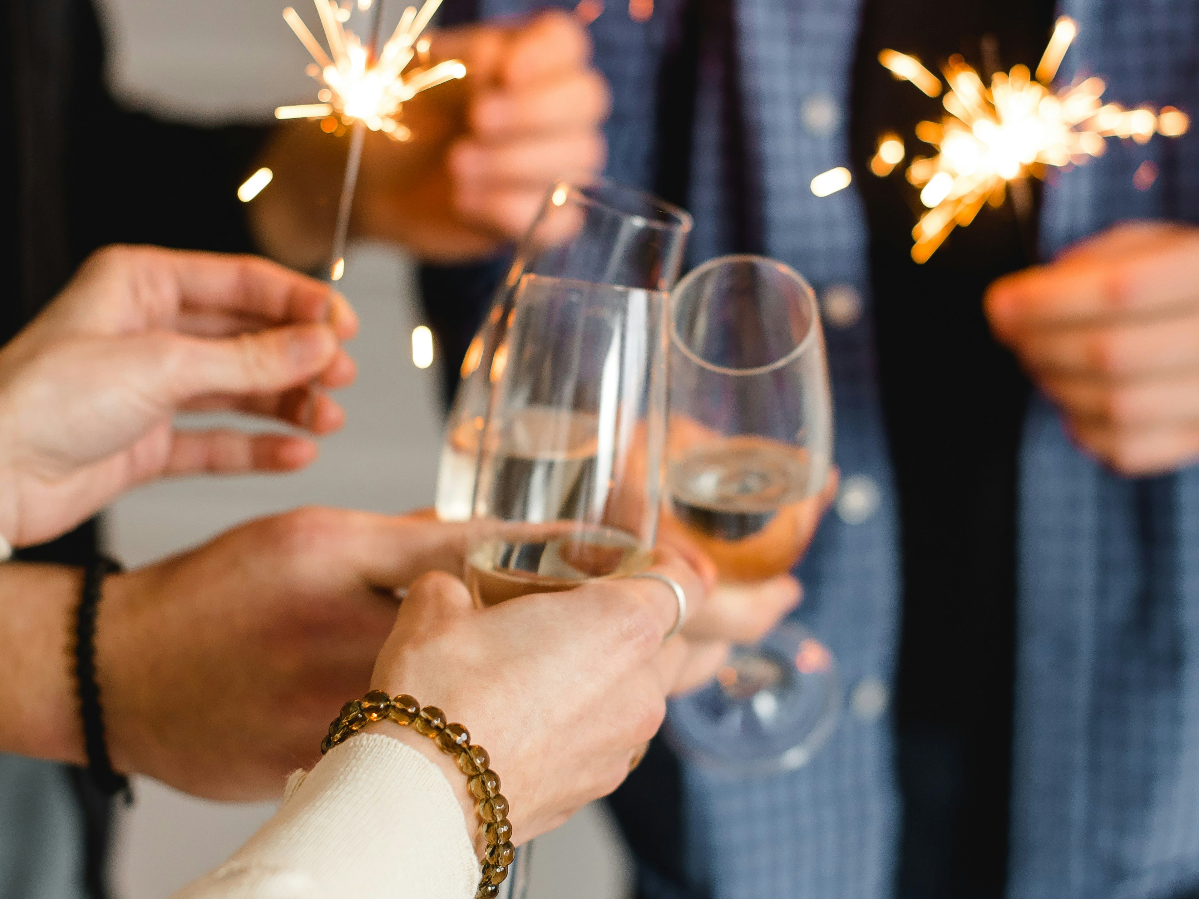 People holding sparklers and clinking champagne glasses in celebration