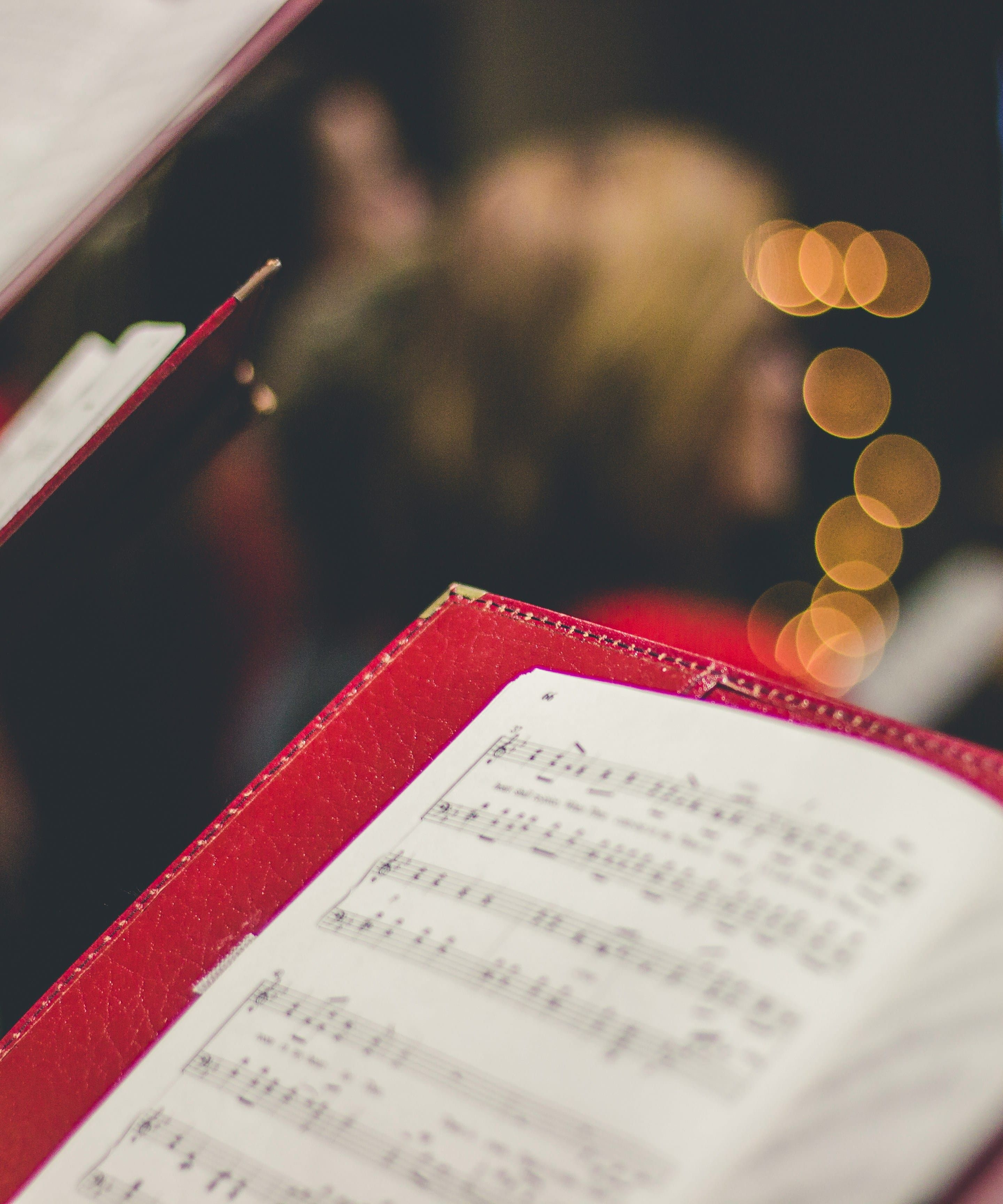 Close-up of sheet music in red folders held by a choir