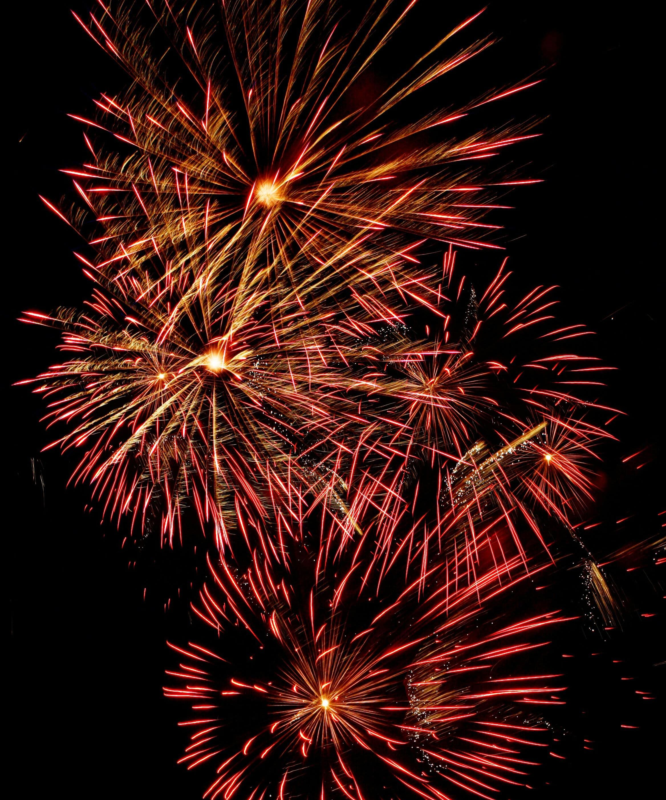 Bright red and gold fireworks bursting against a black night sky
